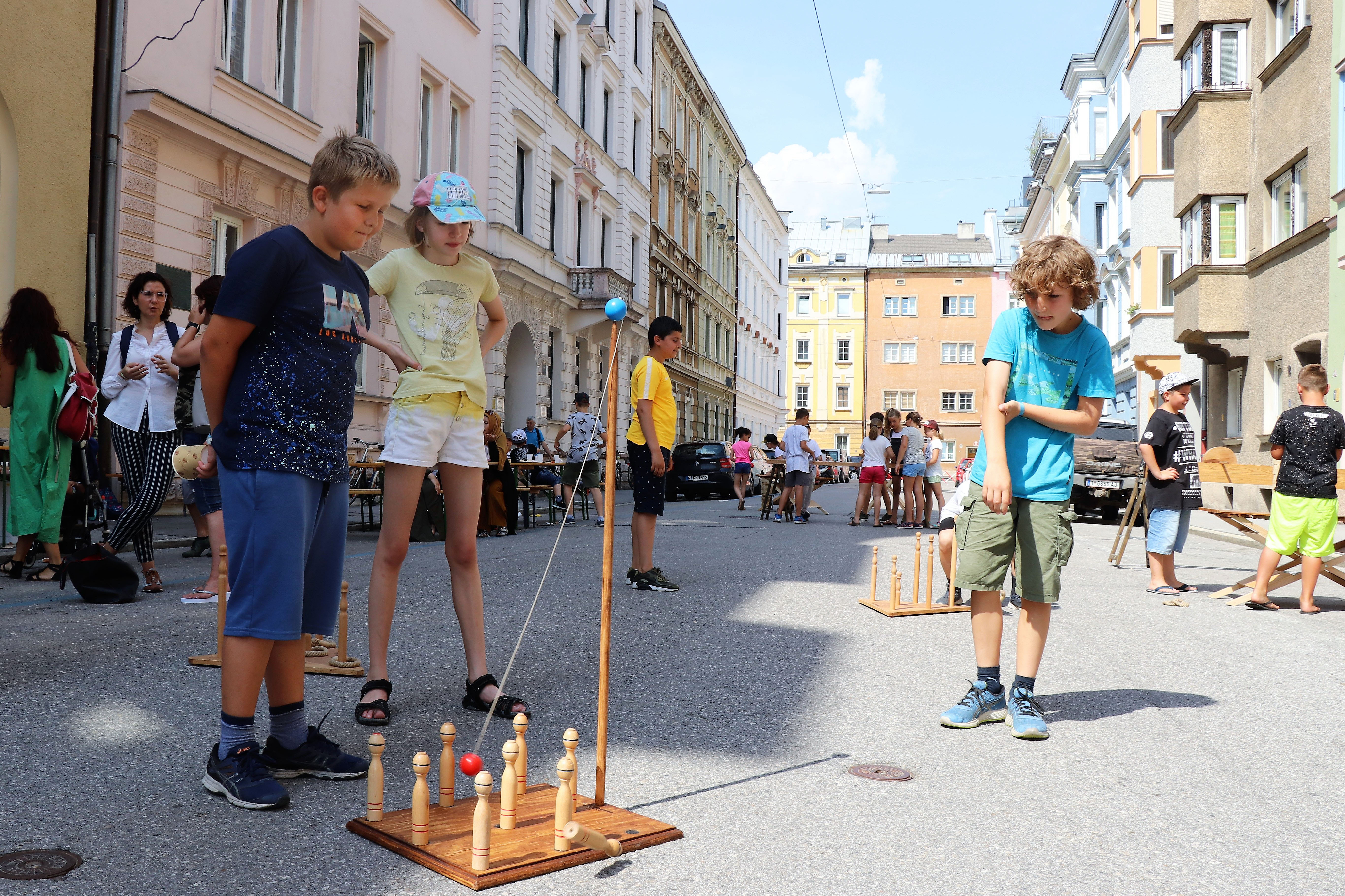 Am 1. Juli begrüßten die SchülerInnen der Volksschule Franz-Fischer-Straße Bürgermeister Georg Willi bei ihrem Sommerfest mit Spielen aus alter Zeit. Nicht nur die Kinder, auch der Bürgermeister waren trotz Hitze mit Feuereifer bei der Sache.