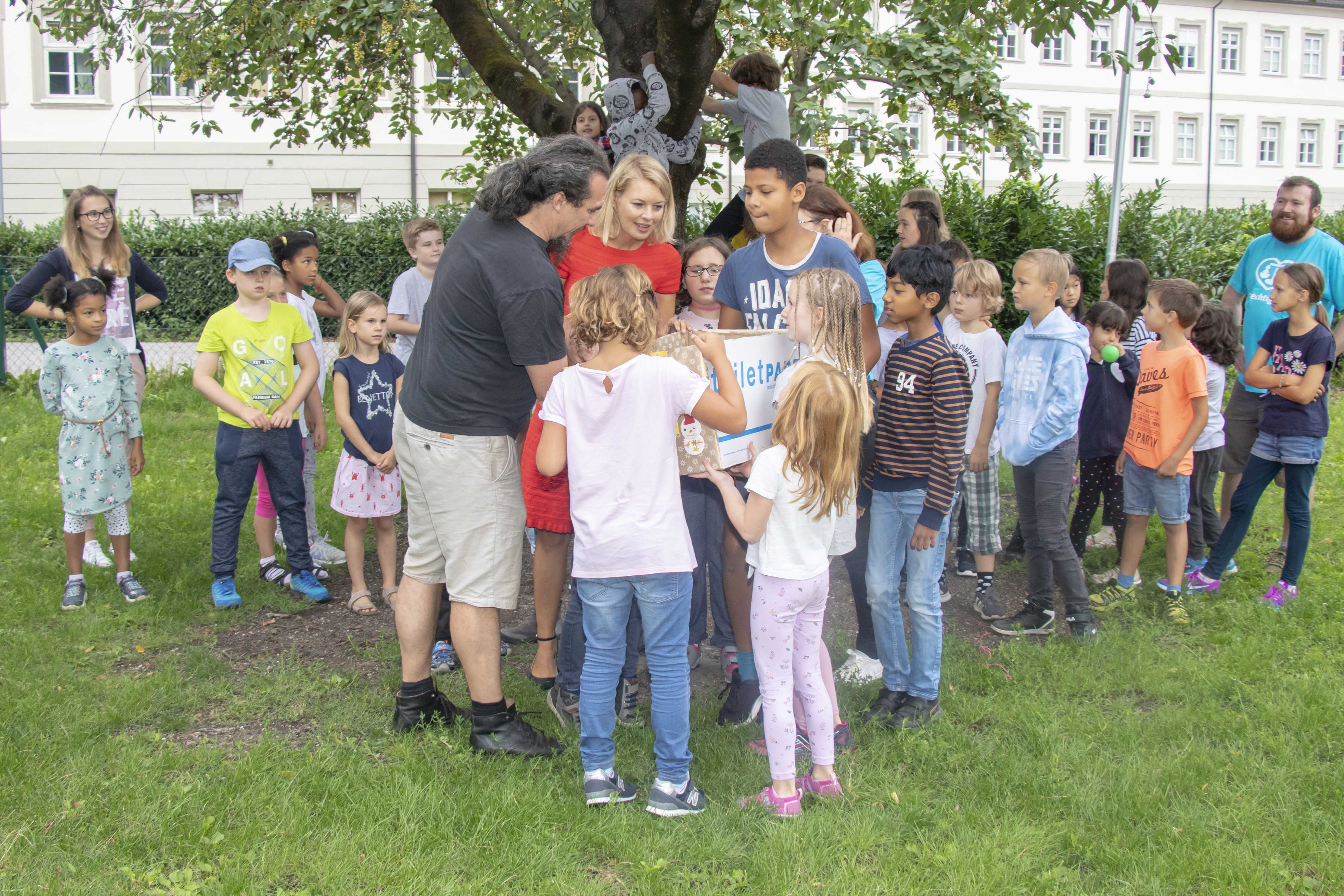 Anlässlich des Endes der Ferienbetreuung im Tagesheim der Kinderfreunde Tirol in der Volkschule Innere Stadt besuchte Stadträtin Mag.a Elisabeth Mayr (Mitte) das Tagesheim und bedankte sich bei den PädagogInnen der Kinderfreunde Tirol für die gelungene Sommerbetreuung. Dem Geschäftsführer des Vereins für Obdachlose, Michael Hennermann (l.), wurde in diesem Rahmen ein Kiste mit Weihnachtsgeschenken für Notleidende übergeben, welche die Kinder während ihrer Zeit im Tagesheim gesammelt haben. Vor allem lang haltbare Lebensmittel sind in der Kiste enthalten, die an die Obdachlosen weitergegeben werden. Neugierig untersuchen Stadträtin Mayr und Geschäftsführer Hennermann gemeinsam mit den Kindern den Inhalt der Kiste und bedankten sich bei Allen für ihr soziales Engagement.