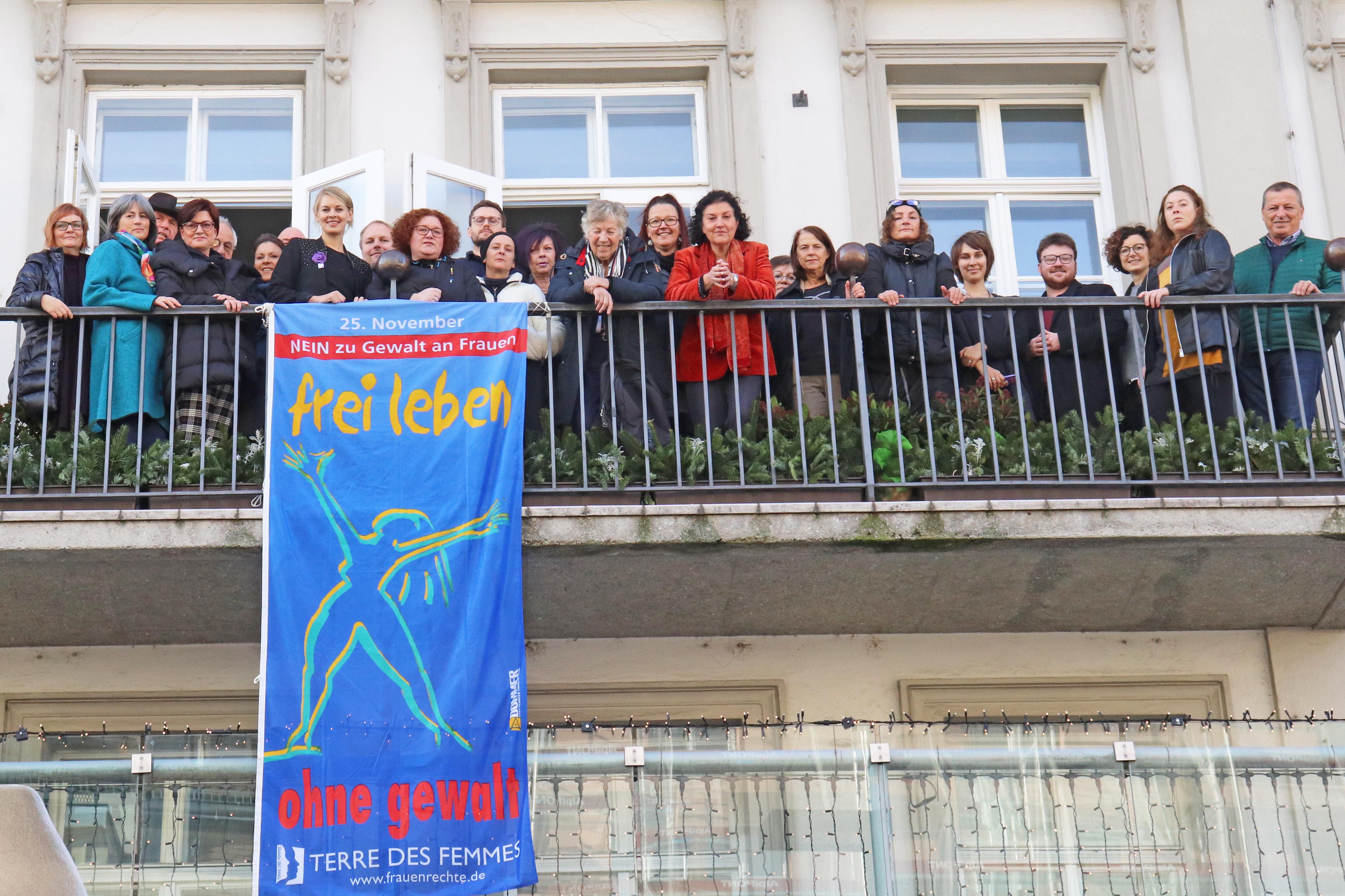 Frauenstadträtin Elisabeth Mayr (vorne, 4. v. l.) und Referatsleiterin Uschi Klee (12. v. r.) hissten gemeinsam mit VertreterInnen der Stadtpolitik, den MitarbeiterInnen der Stadtverwaltung sowie VertreterInnen der Innsbrucker Frauenorganisationen die „Frei leben ohne Gewalt“ am Balkon des Rathauses in der Maria-Theresien-Straße.