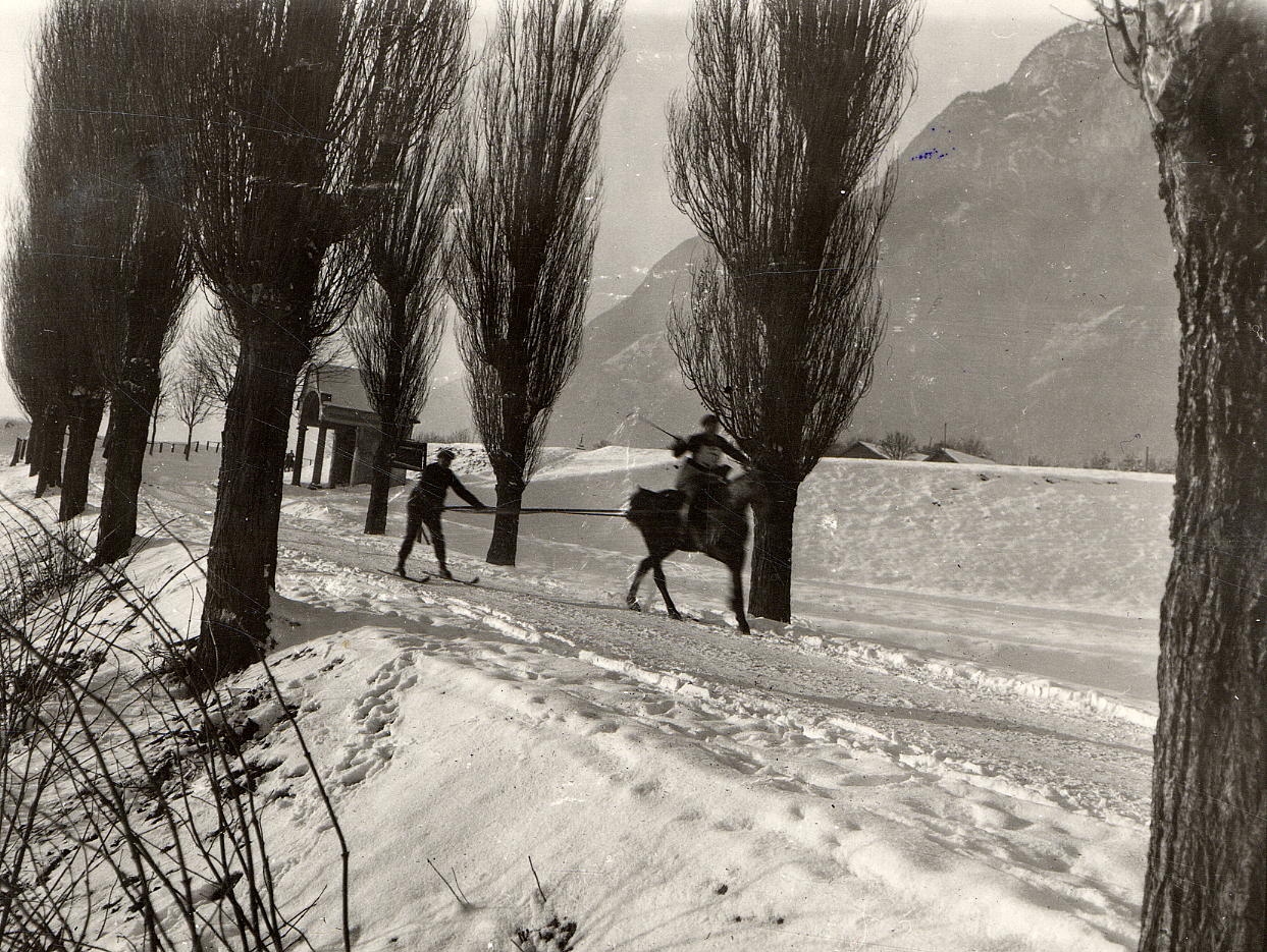 Beim Skijöring wird eine Person auf Skiern von einem Pferd oder Motorrad gezogen. Skijöring war vor allem vor dem Zweiten Weltkrieg beliebt und es wurden jeden Winter mehrere Rennen veranstaltet. Ein beliebtes Skijöring-Rennen führte über die Kranebitter Allee. Start war das Hotel Post in Zirl, Ziel das Gasthaus Rössl in der Au in Innsbruck. Im Bild (1930er-Jahre) ist der westliche Teil der Kranebitter Allee mit der bekannten Kapelle zu sehen.