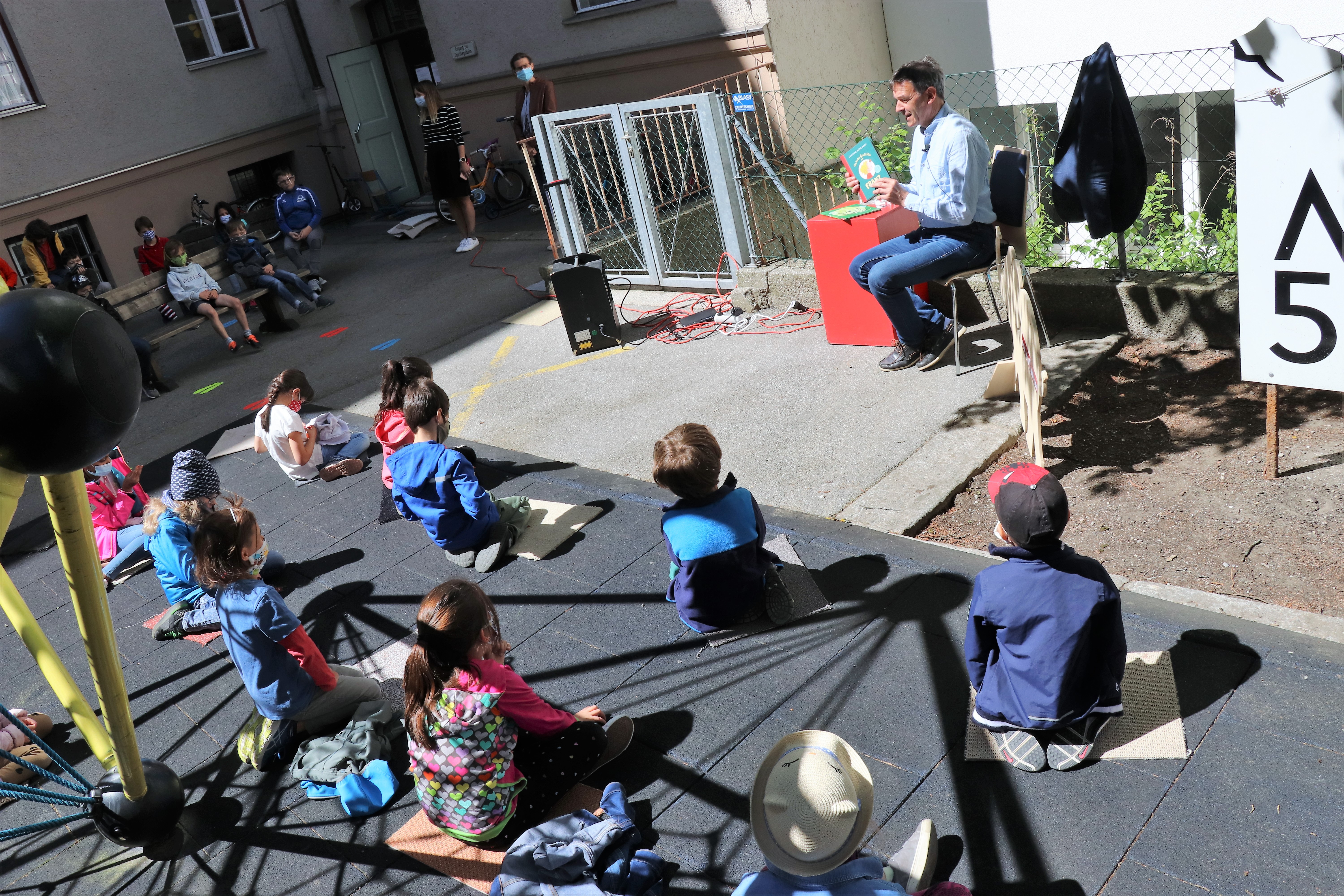 Auch in Zeiten von Corona war die Vorlesestunde mit Bürgermeister Georg Willi in der Volksschule Franz-Fischer-Straße ein großer Erfolg. Die SchülerInnen lachten über Christine Nöstlingers "Geschichten vom Franz" und lernten ganz zeitgemäß mit "Willi Virus" von Heidi Trpak, wie man sich vor Ansteckung schützt. 
Die Vorlesestunde fand im Freien und mit dem erforderlichen Abstand zwischen den Kindern statt. Dafür hatte der Schulleiter Direktor Martin Müller vorbildlich gesorgt: Unter anderem erinnerte auch ein Babyelefant an das notwendige Abstandhalten. Das tat der spürbaren gemeinsamen Freude am Vorlesen und Zuhören aber keinen Abbruch.