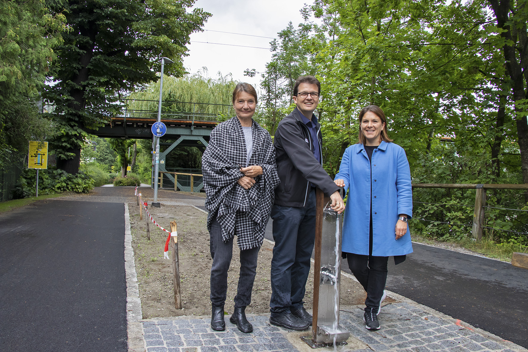 Vizebürgermeisterin Uschi Schwarzl, Referatsleiter Markus Pinter und Gemeinderätin Julia Seidl (v. l.) testeten den neuen Trinkbrunnen bei der Karwendelbrücke. © IKM/Freinhofer