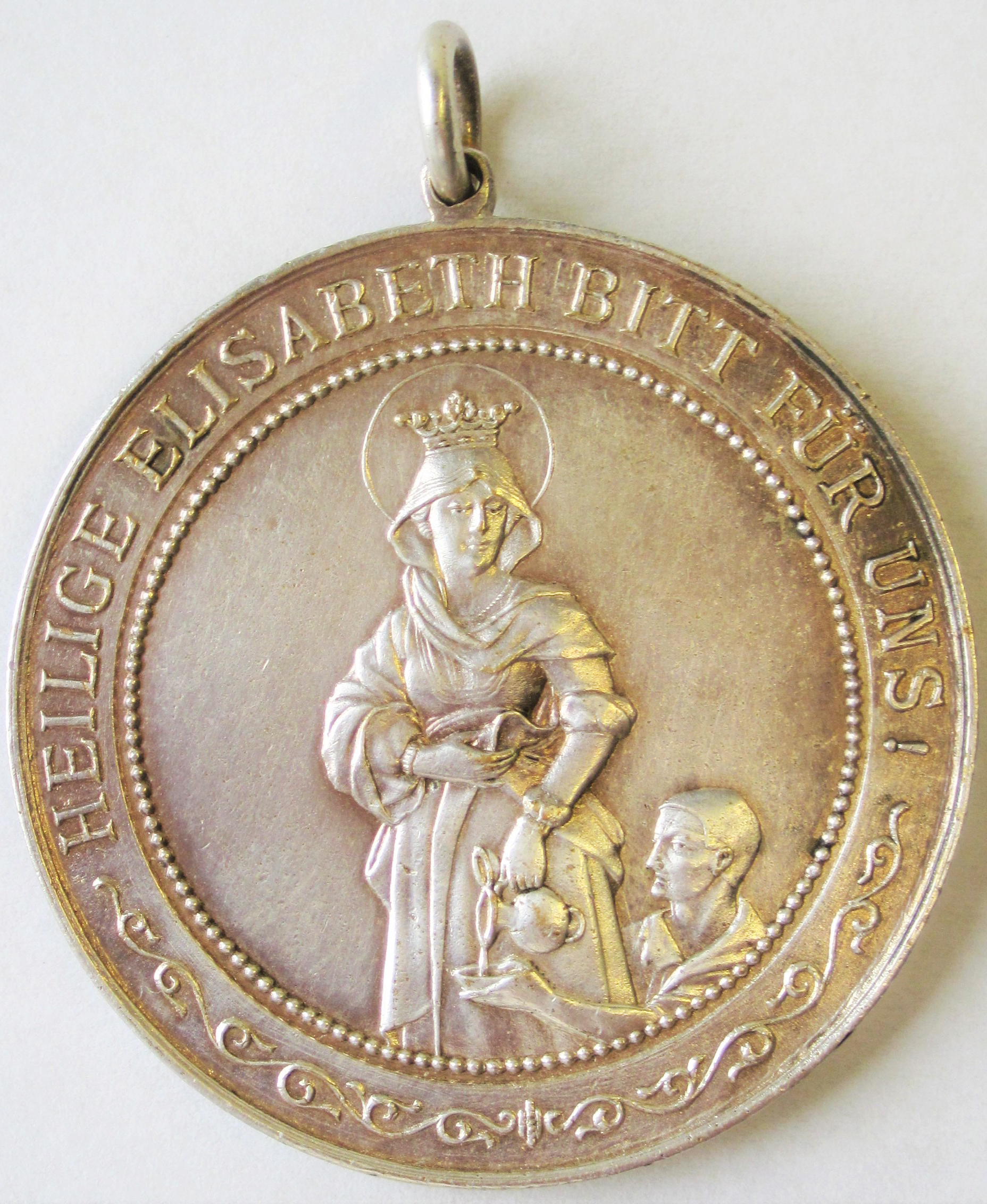 Die hl. Elisabeth von Thüringen gibt einem Durstigen zu trinken. – Medaille der Marianischen Kongregation Bürgerlicher Frauen, Rückseite