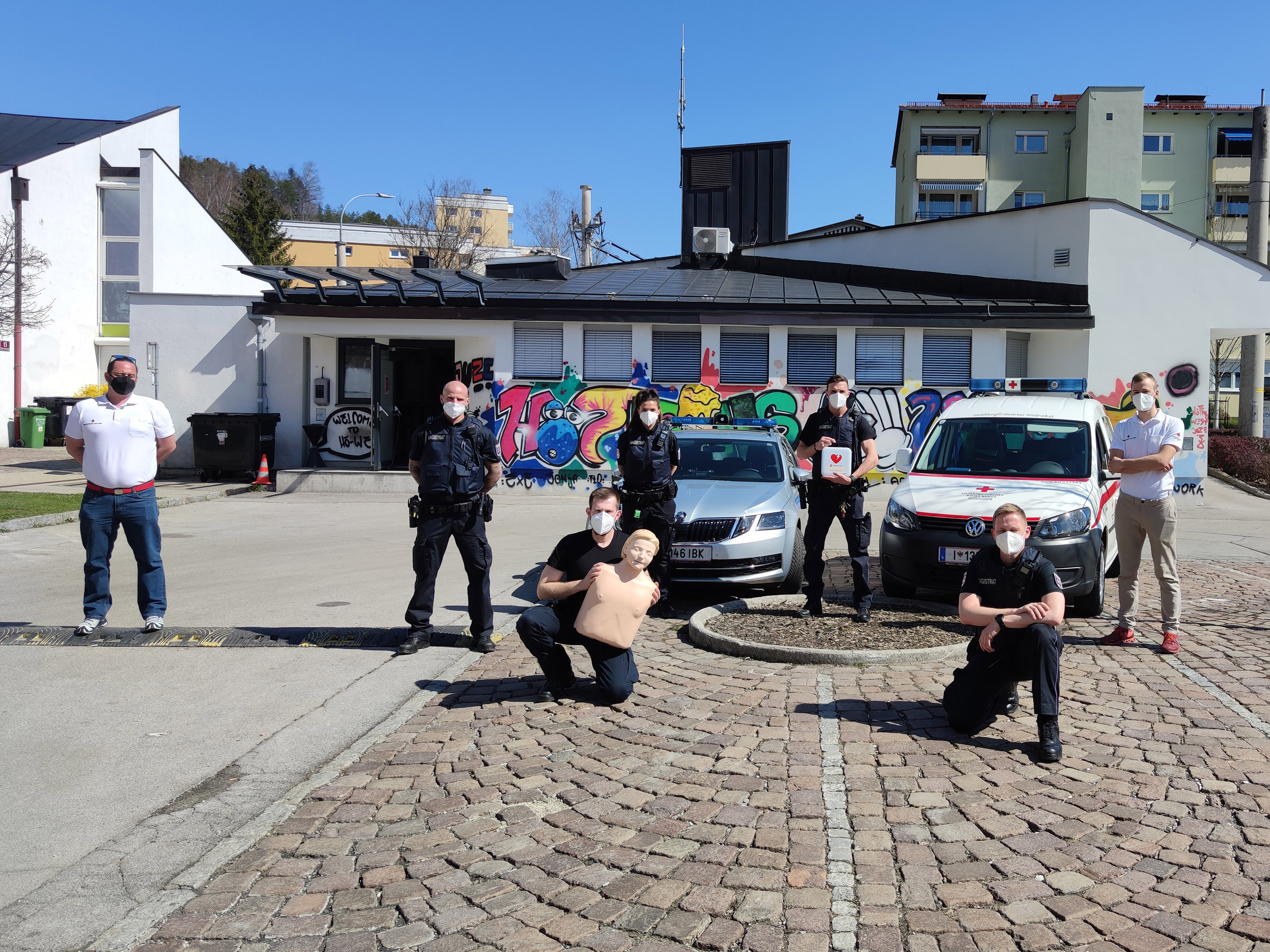 Die MitarbeiterInnen der Mobilen Überwachungsgruppe und des Roten Kreuzes mit dem Defibrillator vor der MÜG-Außenstelle Hötting West.