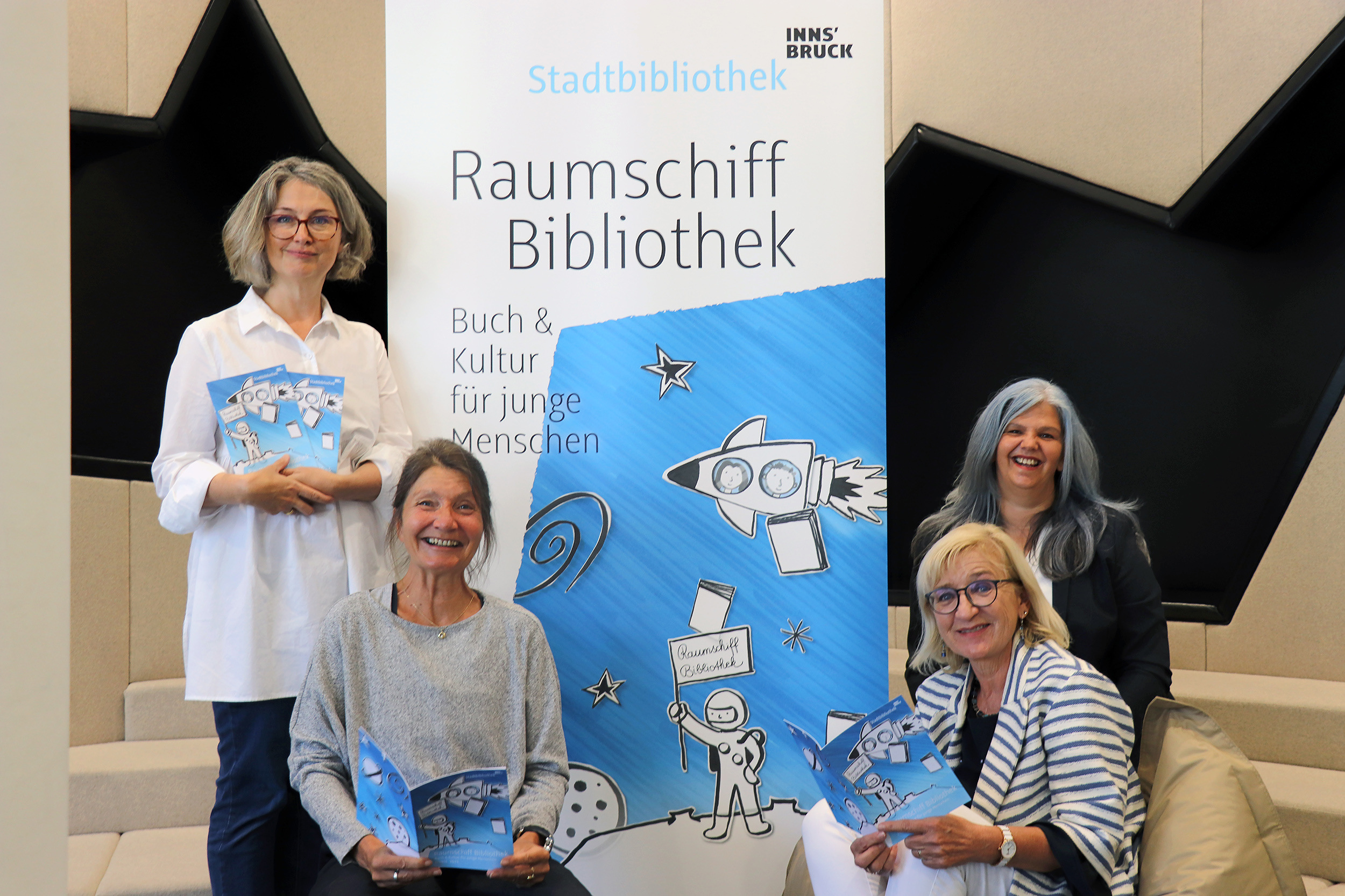 Stadträtin Uschi Schwarzl (vorne li.) und Landesrätin Beate Palfrader (vorne re.) präsentieren gemeinsam mit Veronika Knapp (stehend li.) und Christina Krenmayr von der Stadtbibliothek das neue Programmheft.