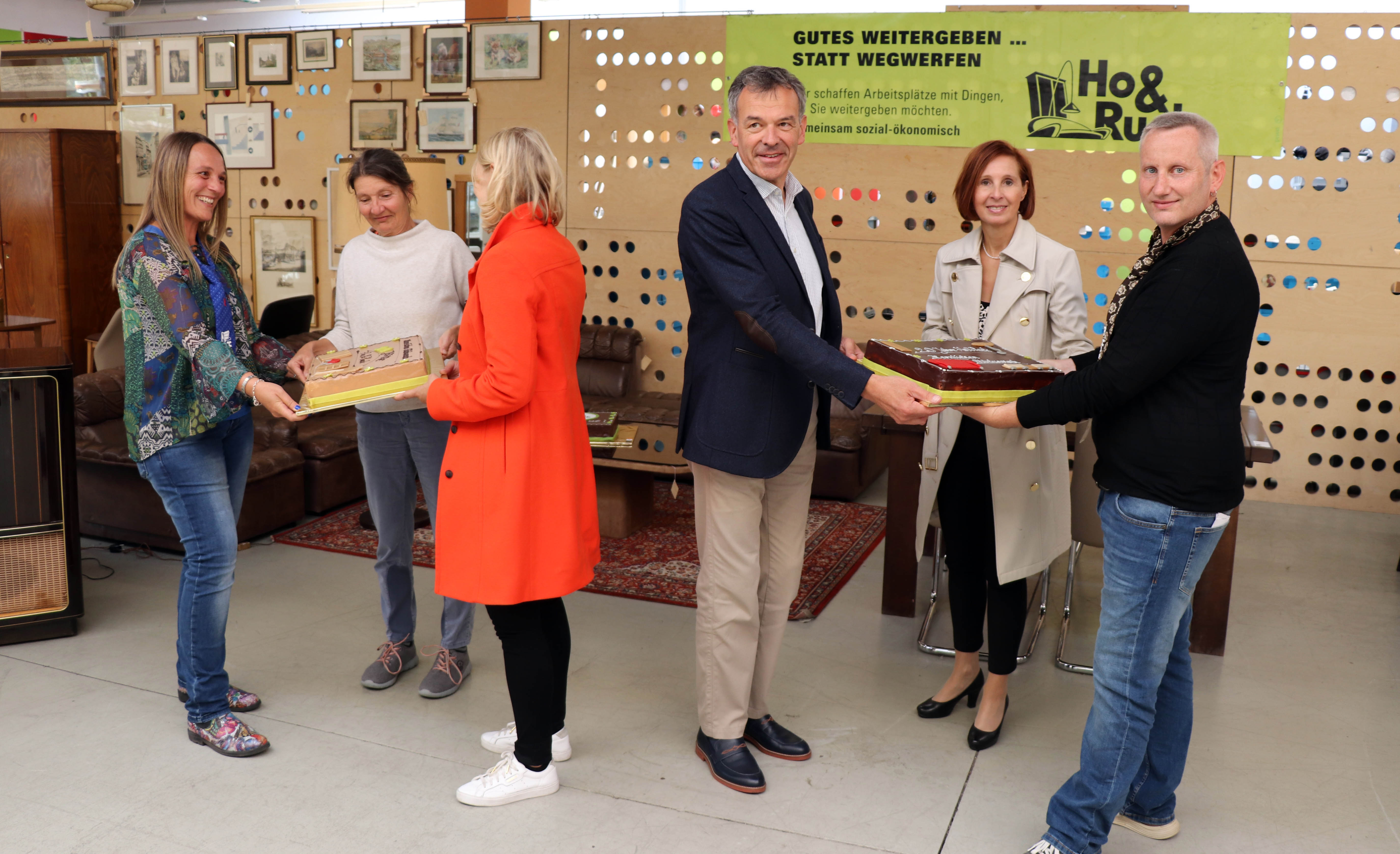 Seit genau 20 Jahren ist das gemeinnützige Unternehmen Ho&Ruck in der ehemaligen Lodenfabrik an der Hallerstraße beheimatet und hat sich zu einer Institution in Innsbruck entwickelt. Bürgermeister Georg Willi (3. v. r.) gratulierte gemeinsam mit den beiden Stadträtinnen Elisabeth Mayr (3. v. l.) und Uschi Schwarzl (2. v. l.) sowie Landesrätin Gabriele Fischer (2. v. r.) anlässlich des runden Jubiläums. Als kleine Aufmerksamkeit überreichten sie zwei prachtvolle Torten an die beiden GeschäftsführerInnen Martina Wolf-Kuntner und Thomas Holzer.