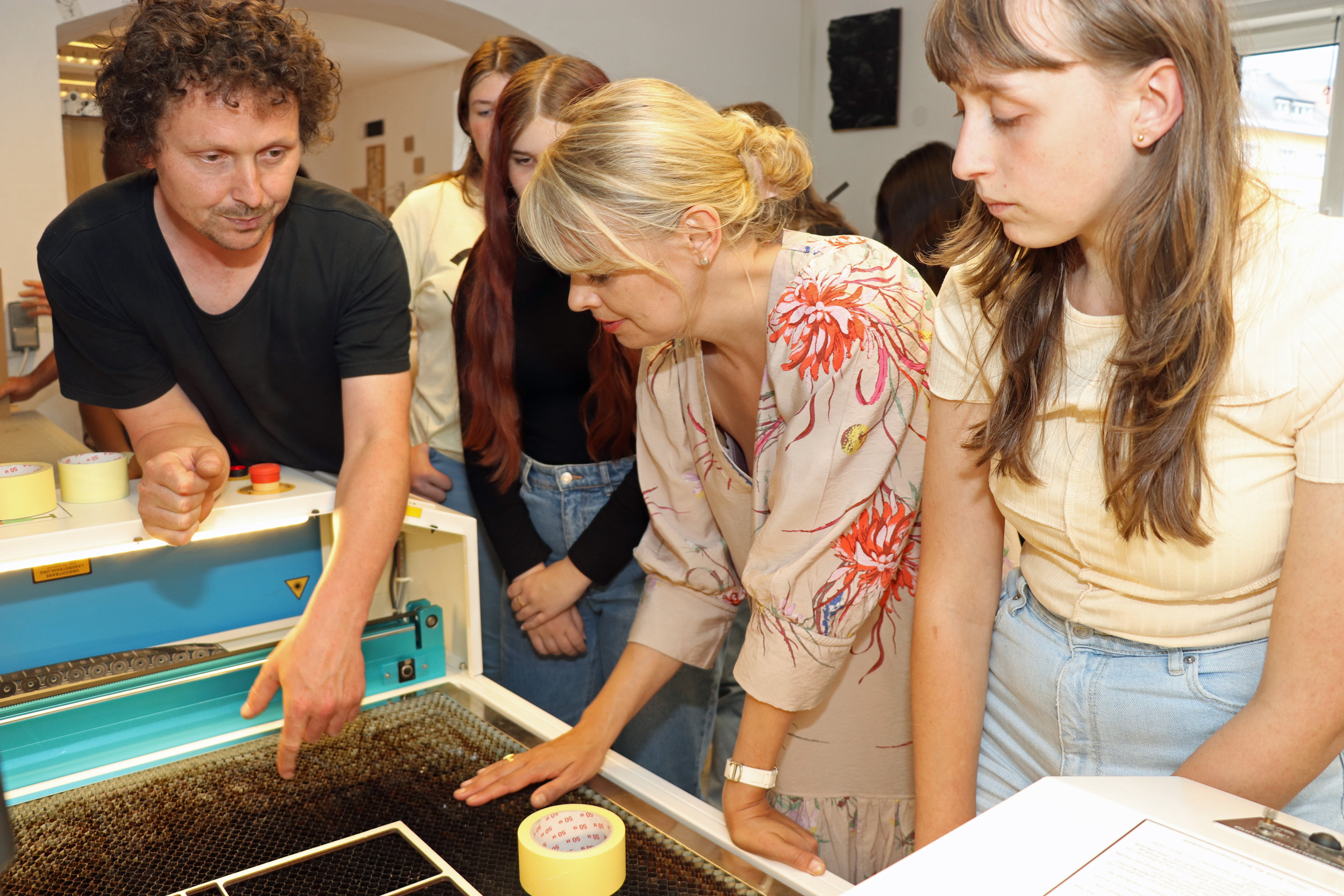 Stadträtin Elisabeth Mayr (M.) lässt sich von einem der FabLab-Gründer, Stefan Strappler (l.), und Schülerinnen der MS Ilse-Brüll-Gasse die Funktionsweise des Laser-Cutters erklären.
