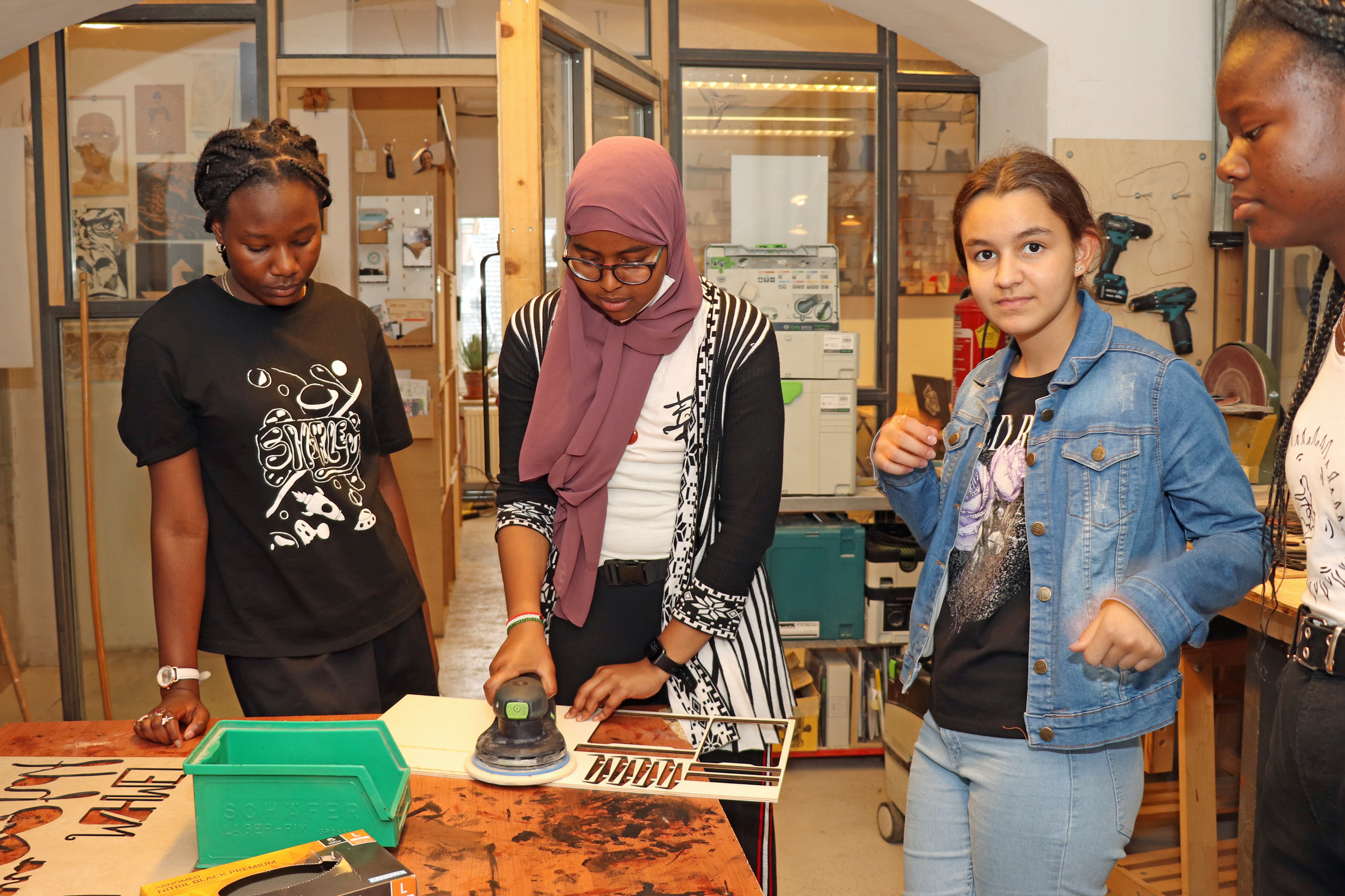 Schülerinnen der MS Ilse-Brüll-Gasse beim Schleifen des im Laser-Cutter gefertigten Holzwerkstücks.