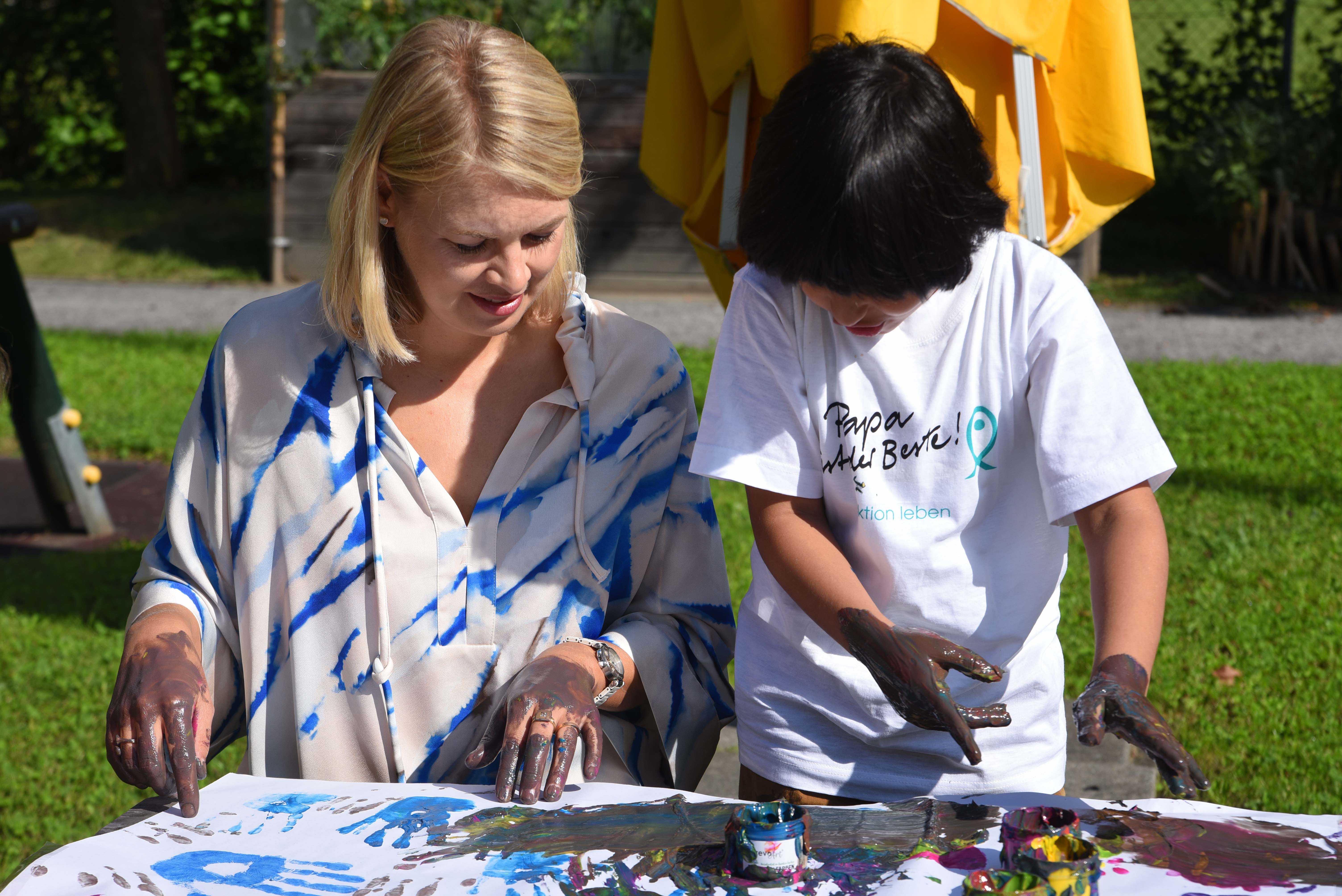 Auch Stadträtin Elisabeth Mayr malt am gemeinsamen Kunstwerk der Kinder mit.
