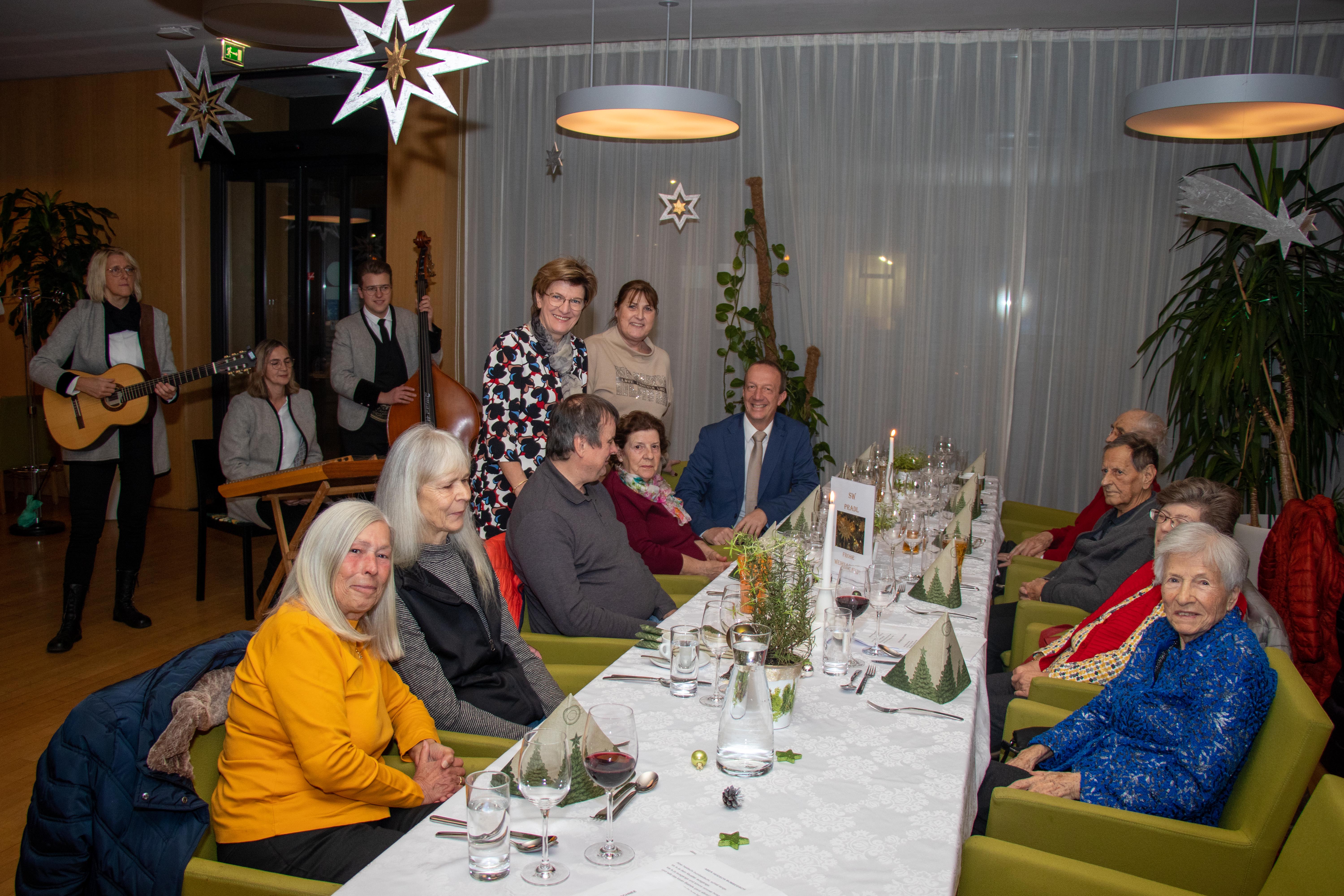 Stadträtin Christine Oppitz-Plörer (stehend, l.) Christine Kurz (Leitung ISD-SeniorInnenwohnen, stehend, r.) und Stefan Hetzenauer (ISD-Wohnanlagen Pradl und O-Dorf 3, r.) feierten mit den SeniorInnen im Wohnheim Tivoli. Auch für musikalische Unterhaltung war gesorgt.