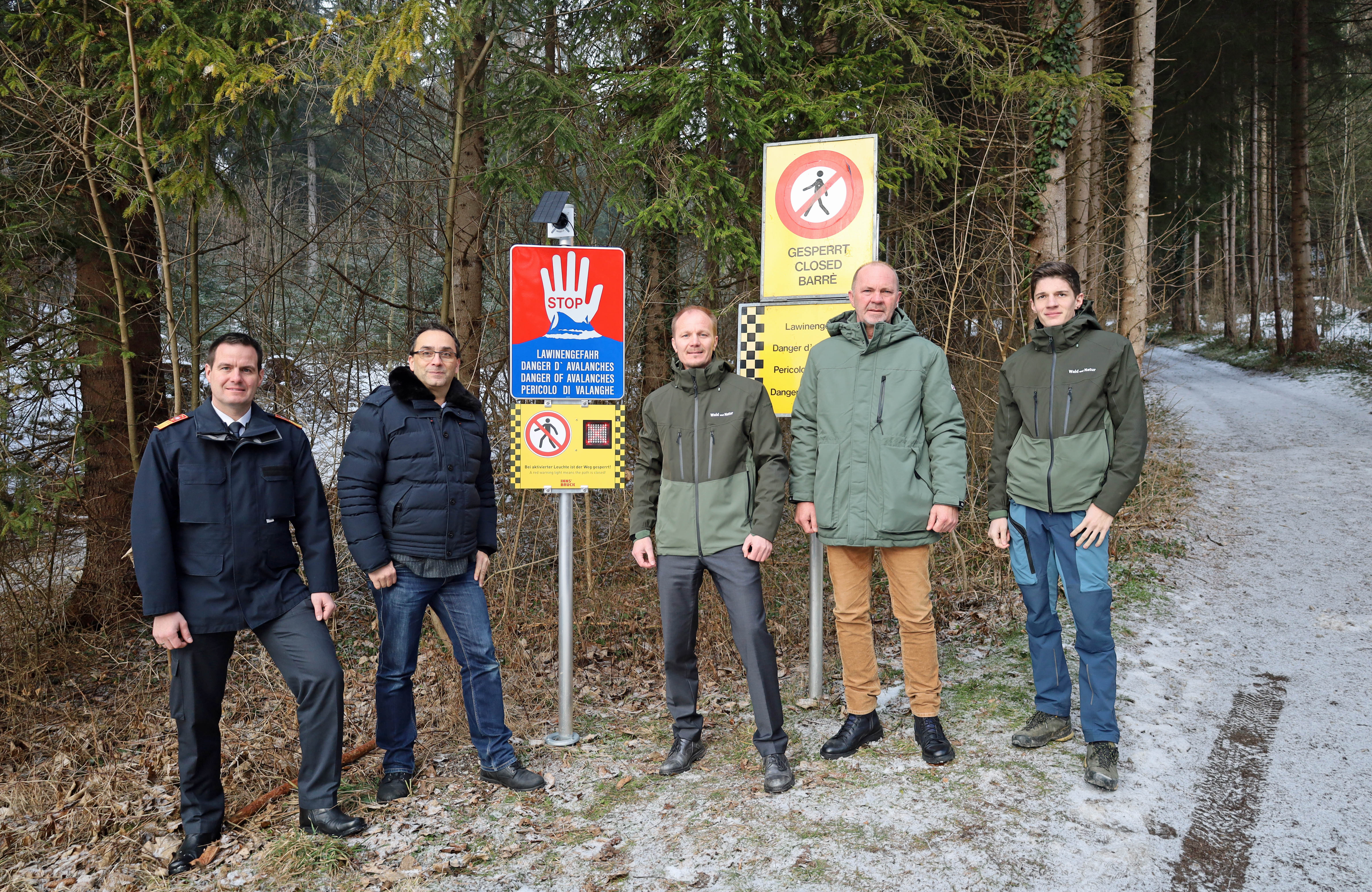 Vizebürgermeister Johannes Anzengruber (3.v.r.), Branddirektor Helmut Hager (l.), die Referenten Thomas Koland (2.v.r.) und Florian Jäger (r.) und Branchenleiter Kamran Kiafar (2.v.l.) vor der digitalen Lawinenwarntafel am Innsbrucker Gramartboden.