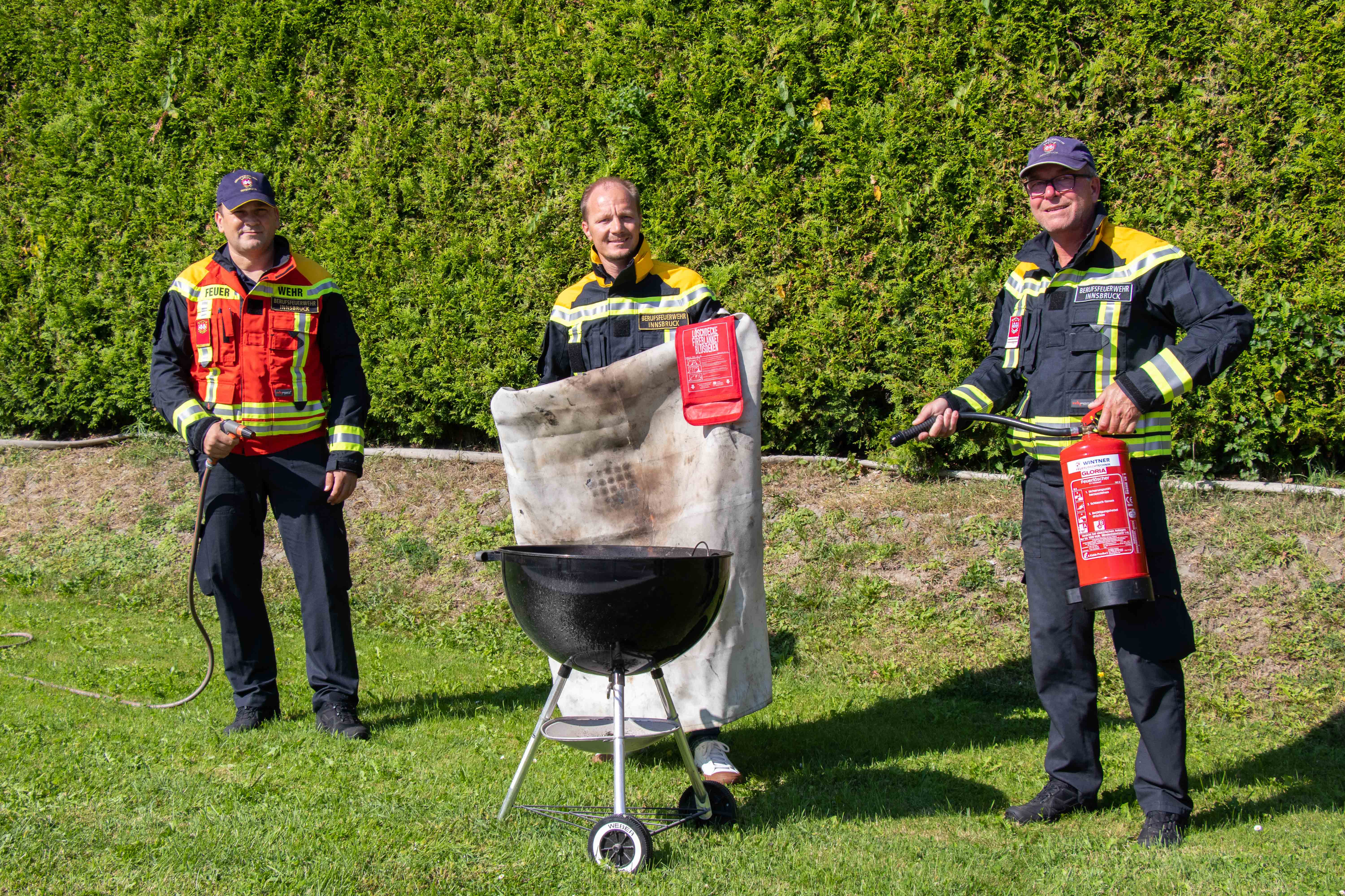 Bekannte Löschmittel sind der klassische Feuerlöscher, Löschdecken oder auch ein Gartenschlauch: Vizebürgermeister Johannes Anzengruber (M.), Brandadjunkt Engelbert Stern (l.) und Oberbrandmeister Bernhard Egger (r.) bei einer Vorführung der Berufsfeuerwehr Innsbruck zum Thema „Sicheres Grillen“.
