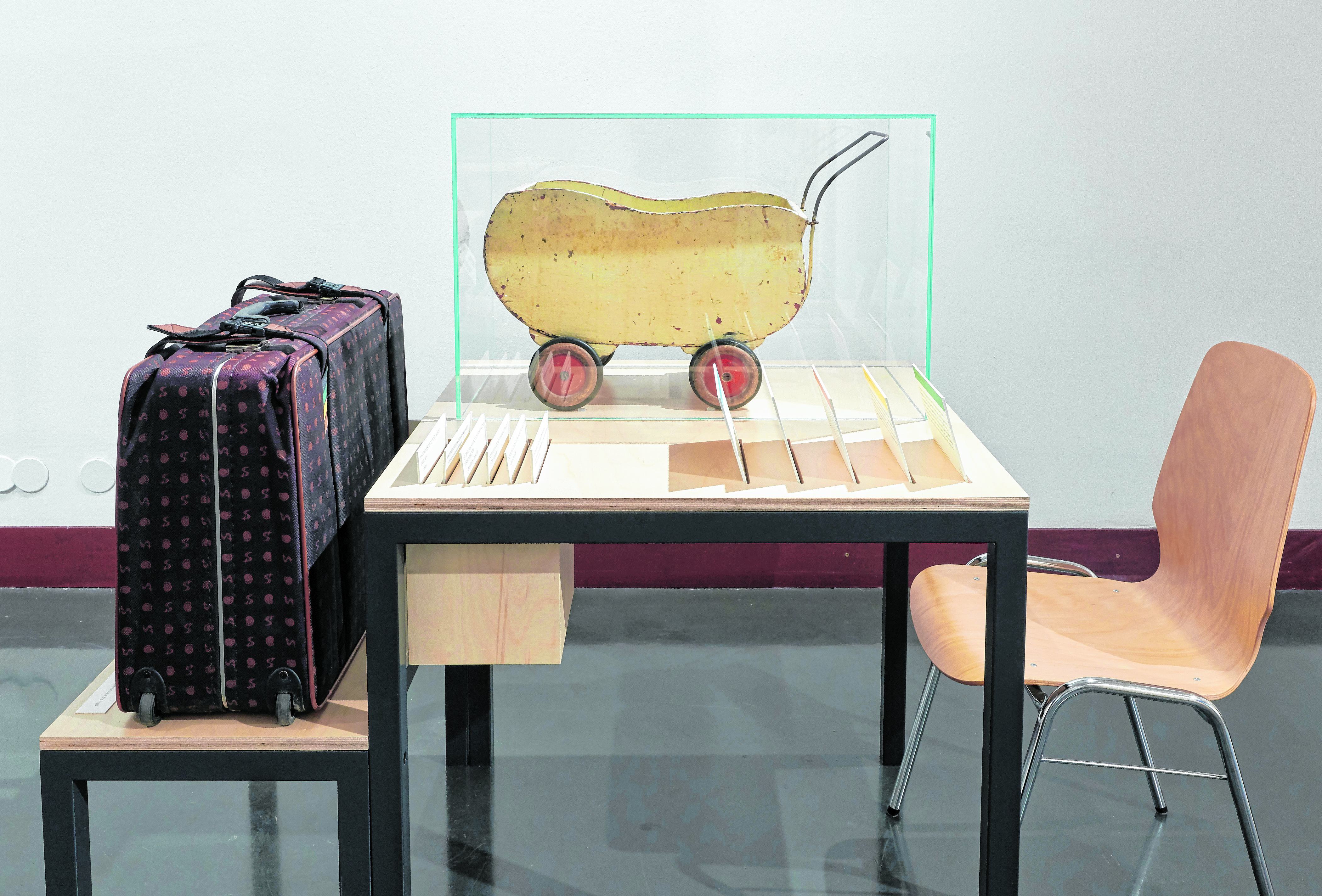 Puppenwagen, aus einer Wehrmachtskiste mit Raubgut aus Frankreich getischlert. Daneben der Koffer, in dem dieses Objekt dem hdgö von der Besitzer-Familie übergeben wurde.