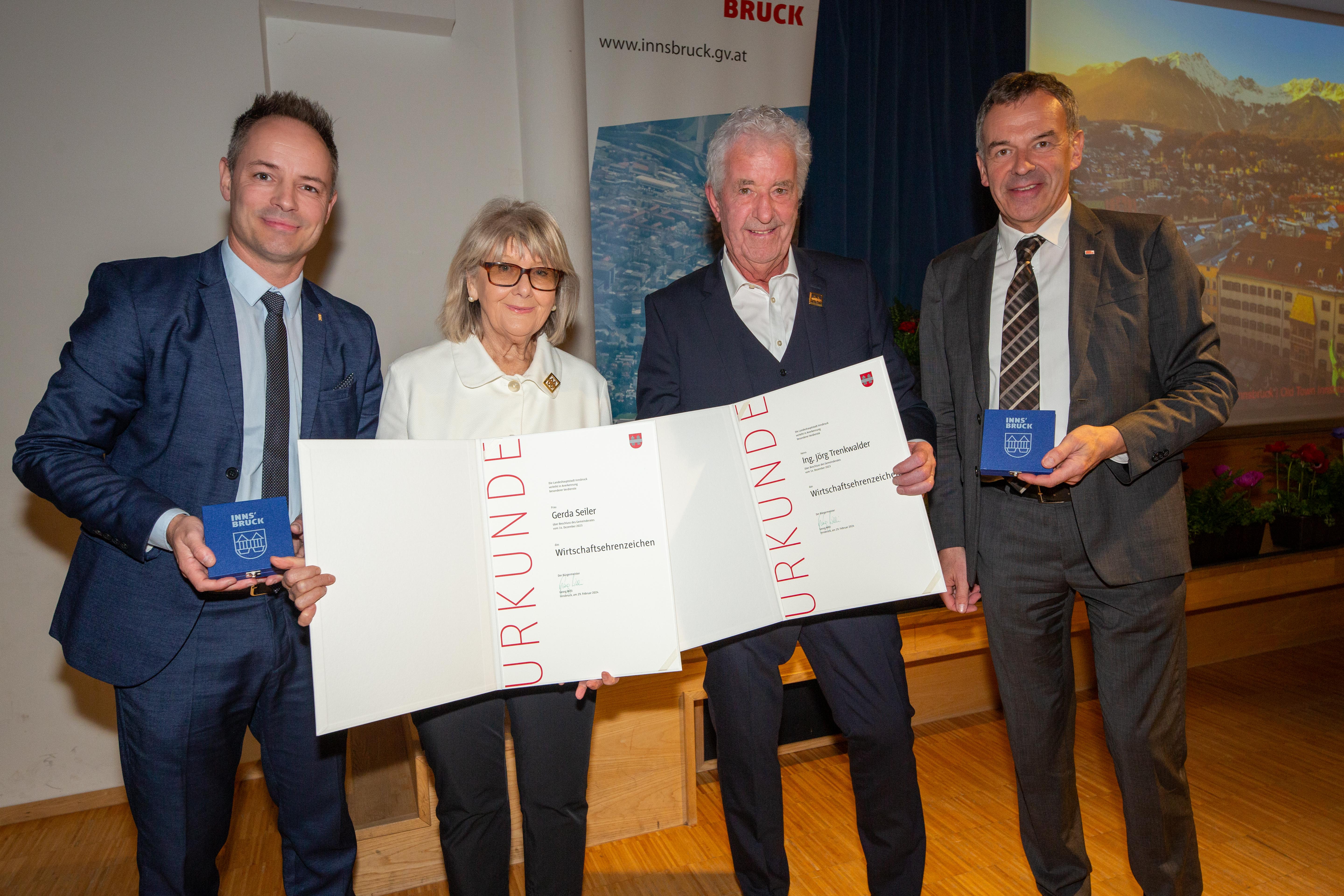 Vizebürgermeister Markus Lassenberger, Gerda Seiler, Jörg Trenkwalder und Bürgermeister Georg Willi freuen sich über die Verleihung der beiden Wirtschaftsehrenzeichen.