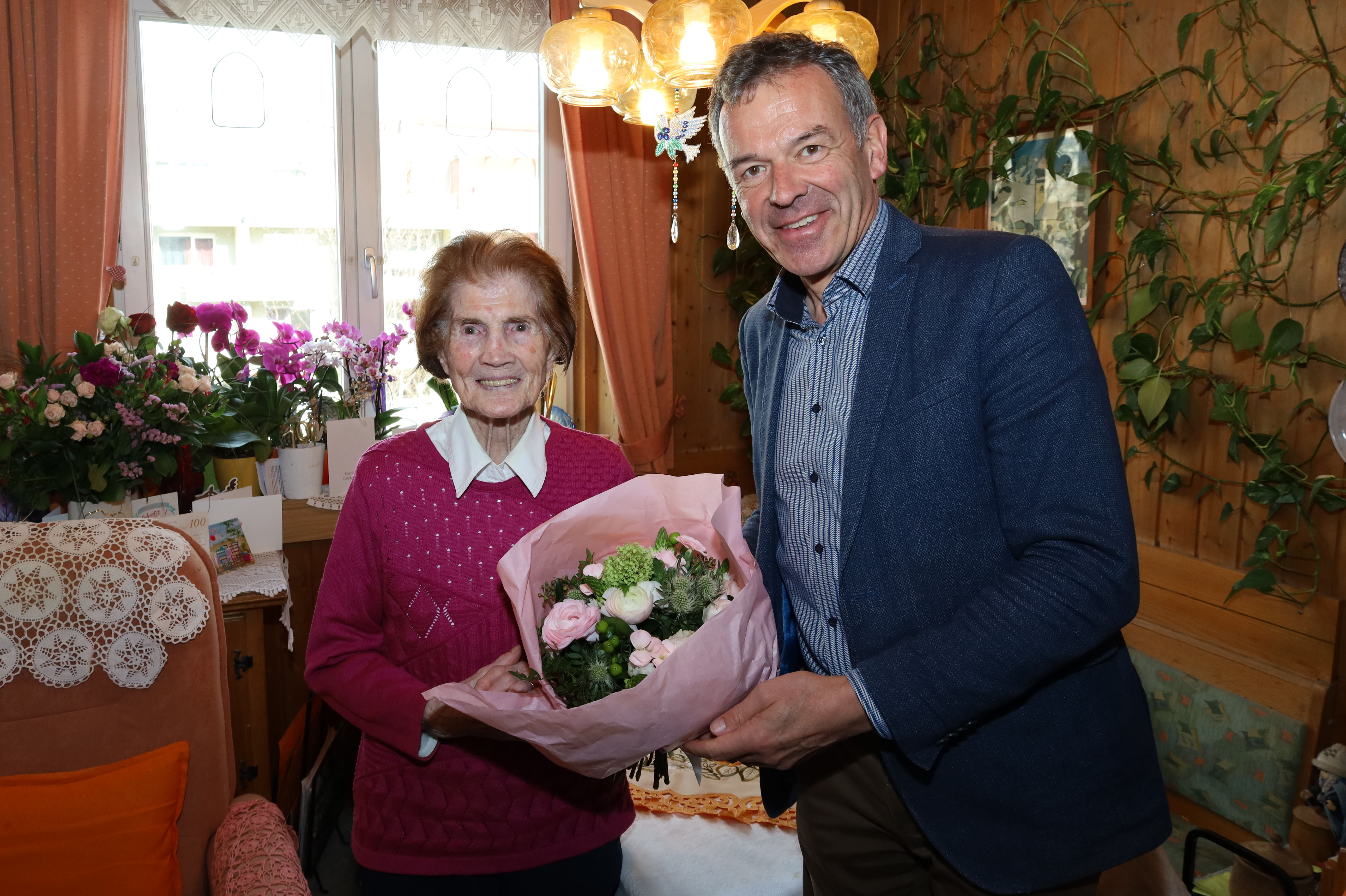 Bürgermeister Georg Willi (r.) überreicht Maria Weger einen Blumenstrauß zum 100. Geburtstag.