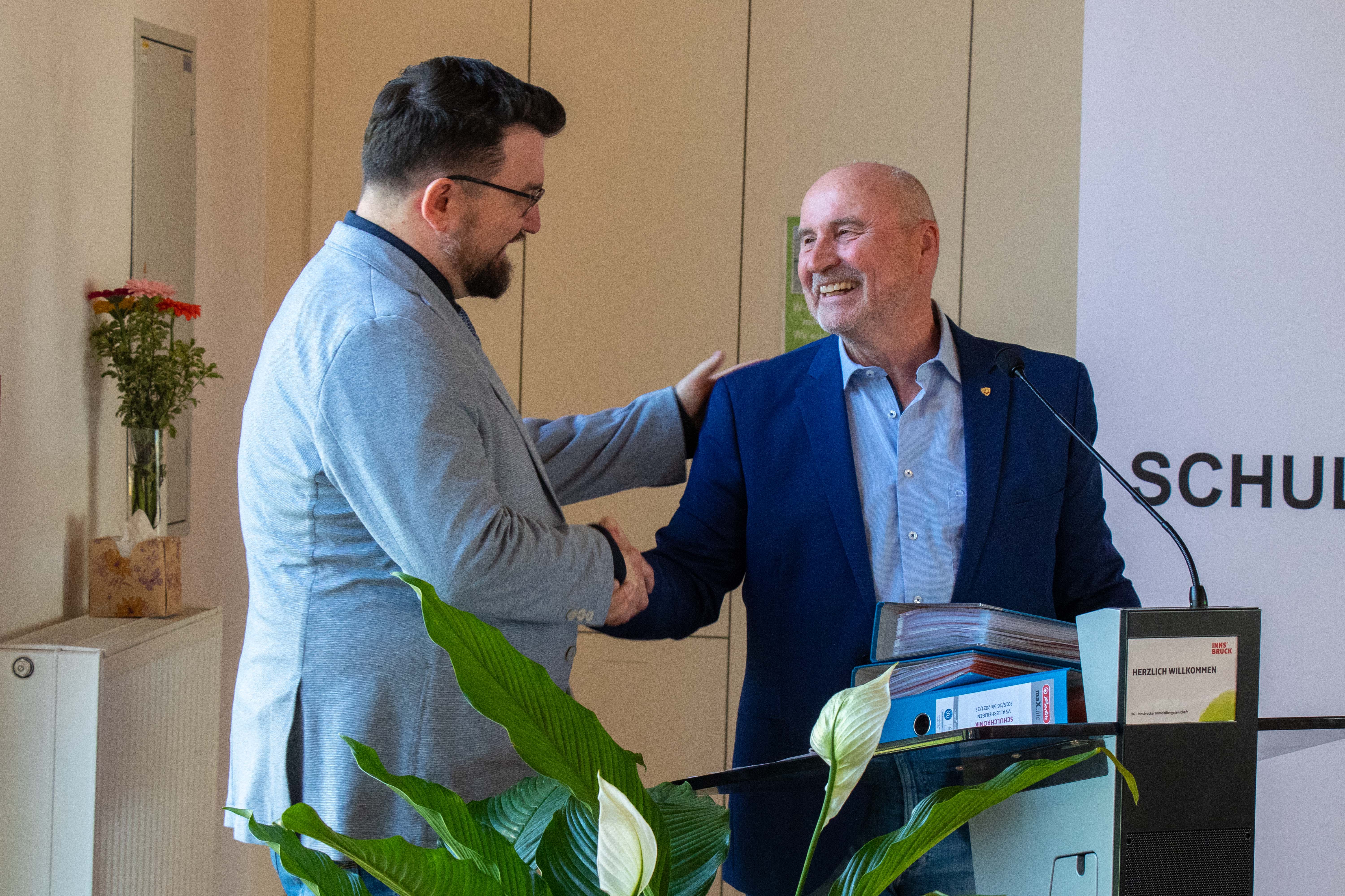 Übergabe der Schulchronik der vergangenen Amtszeit des ehemaligen Direktors Bernhard Bramböck: Sein Nachfolger Direktor Martin Müller nahm die schweren Ordner entgegen.