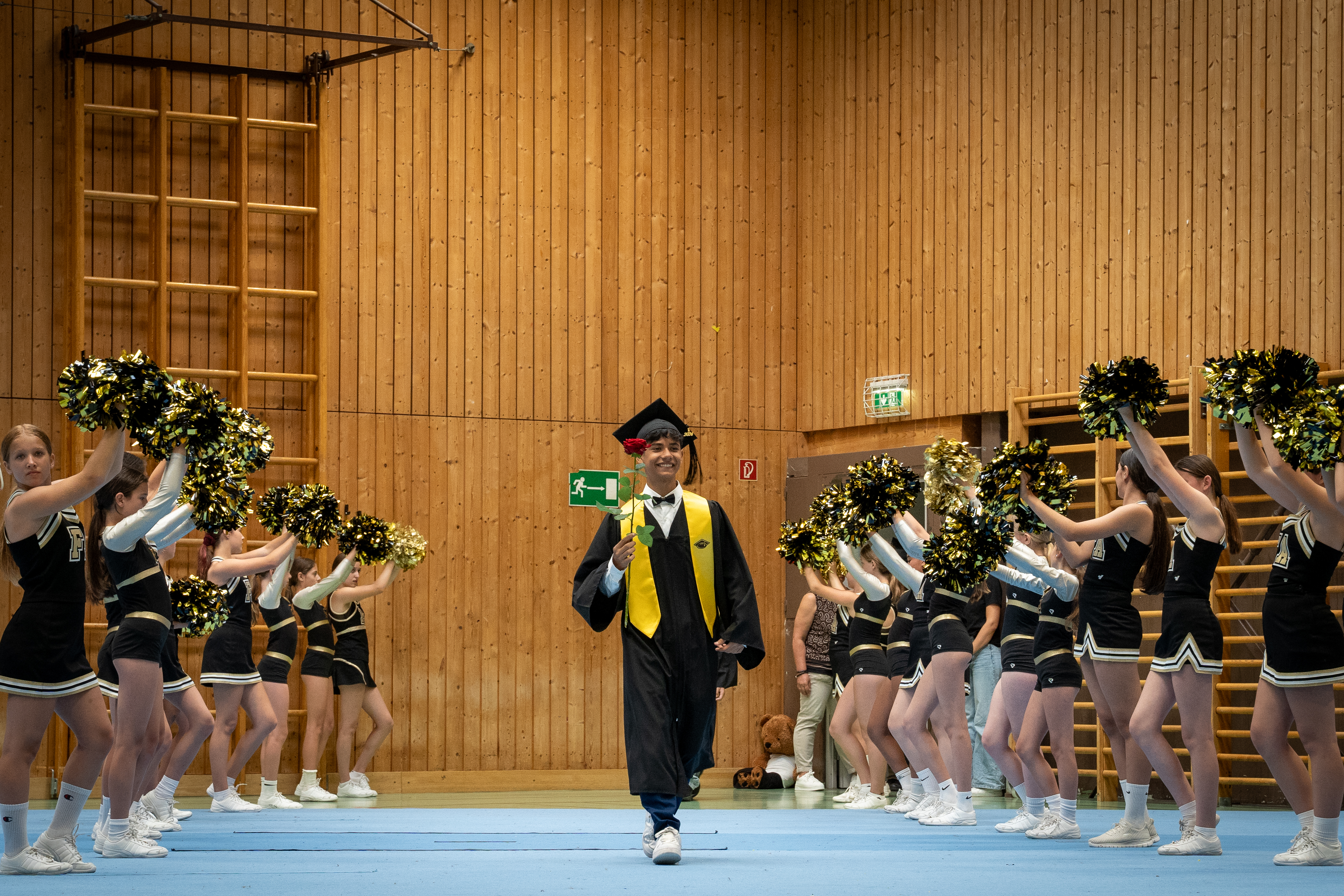 Absolvent Milad Hassanzada schreitet feierlich in den zum Festsaal umfunktionierten Turnsaal der MS Hötting-West.