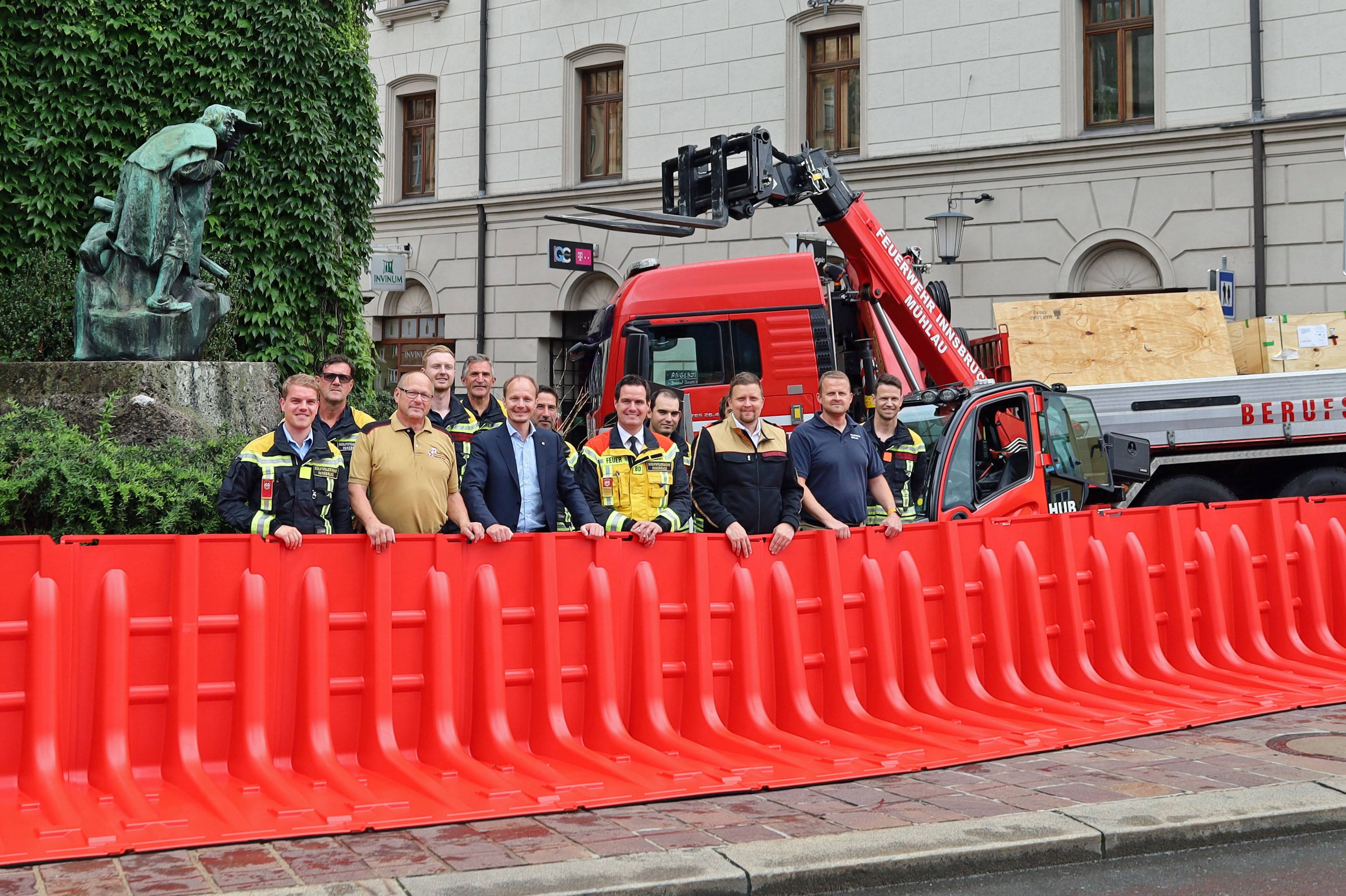 Bürgermeister Johannes Anzengruber (1.R., 3.v.l.), Bezirks-Feuerwehrkommandant Gerhard Mayreger (1.R.,2.v.l.) Branddirektor Helmut Hager (1.R., 4.v.l.), Offizier Manuel Schieferle (l.), Kommandant Lukas Pfeifhofer (FF Mühlau, 1.R. 3.v.r.) und weitere Einsatzkräfte der Feuerwehr bei einer Übung mit dem neuen Hochwasserschutz am Eingang der Altstadt.