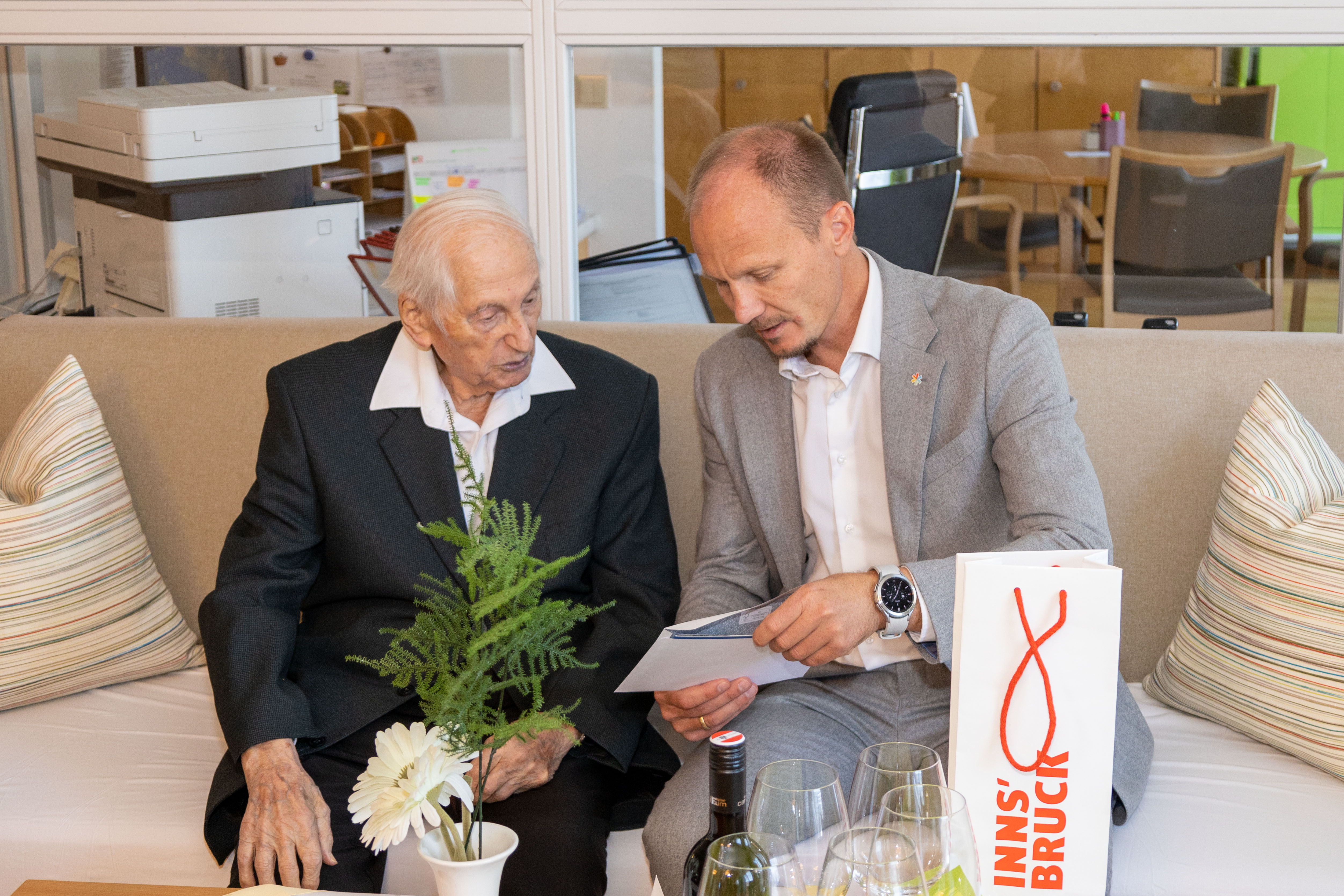 Bürgermeister Johannes Anzengruber (r.) überreichte Ludwig Ascher zum 104. Geburtstag eine Glückwunschkarte der Stadt Innsbruck und eine Flasche Wein.