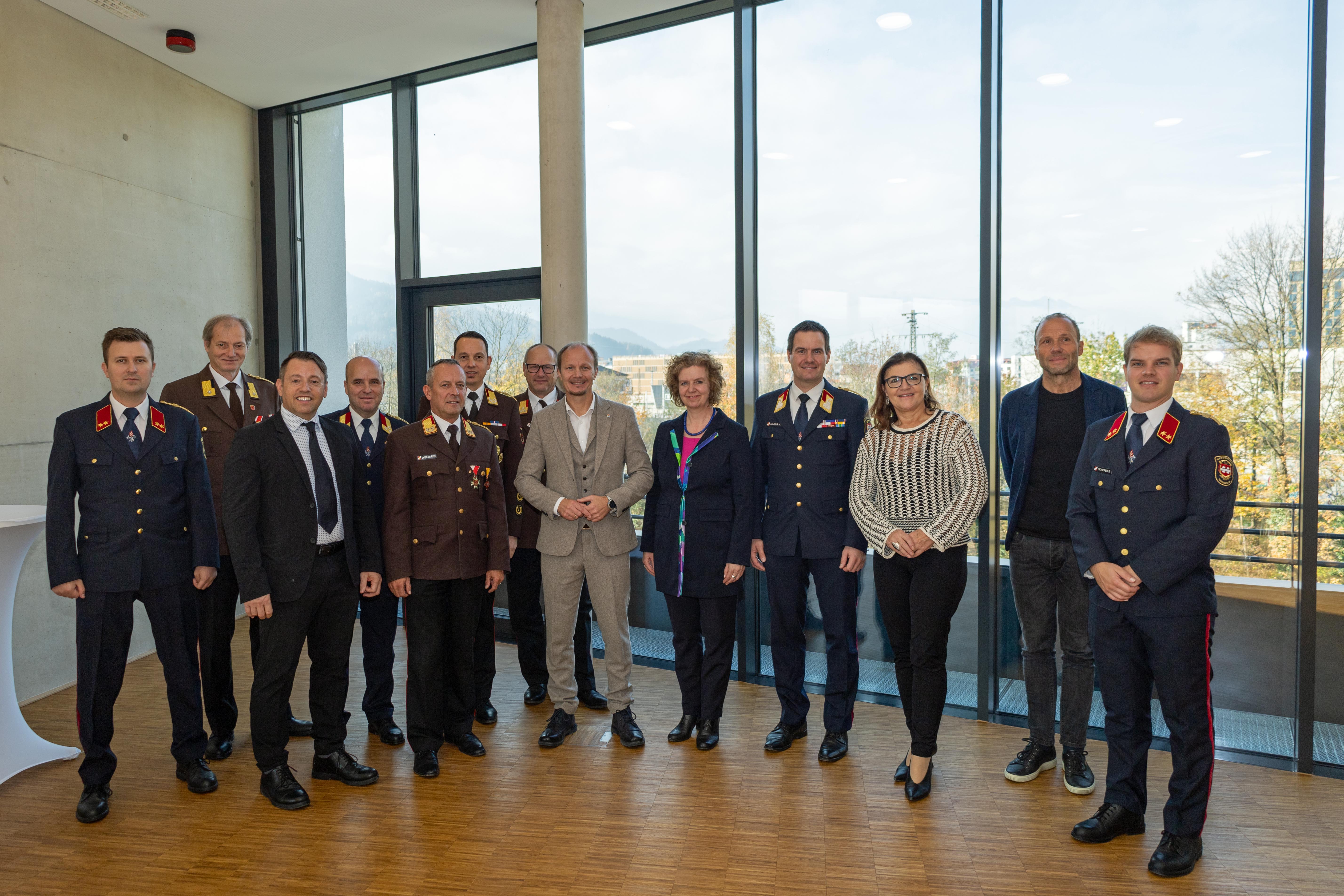 Bürgermeister Johannes Anzengruber (6.v.r.), Magistratsdirektorin Gabriele Herlitschka (5.v.r.), Branddirektor Helmut Hager (4.v.r.), IIG-Geschäftsführer Franz Danler (3.v.l.), Architekt Sebastian Neuschmid (2.v.r.) und Rotes-Kreuz-Geschäftsführerin Alexandra Tanda (3.v.r.) und die Funktionäre der Feuerwehr bei der Übergabefeier im Neubau.