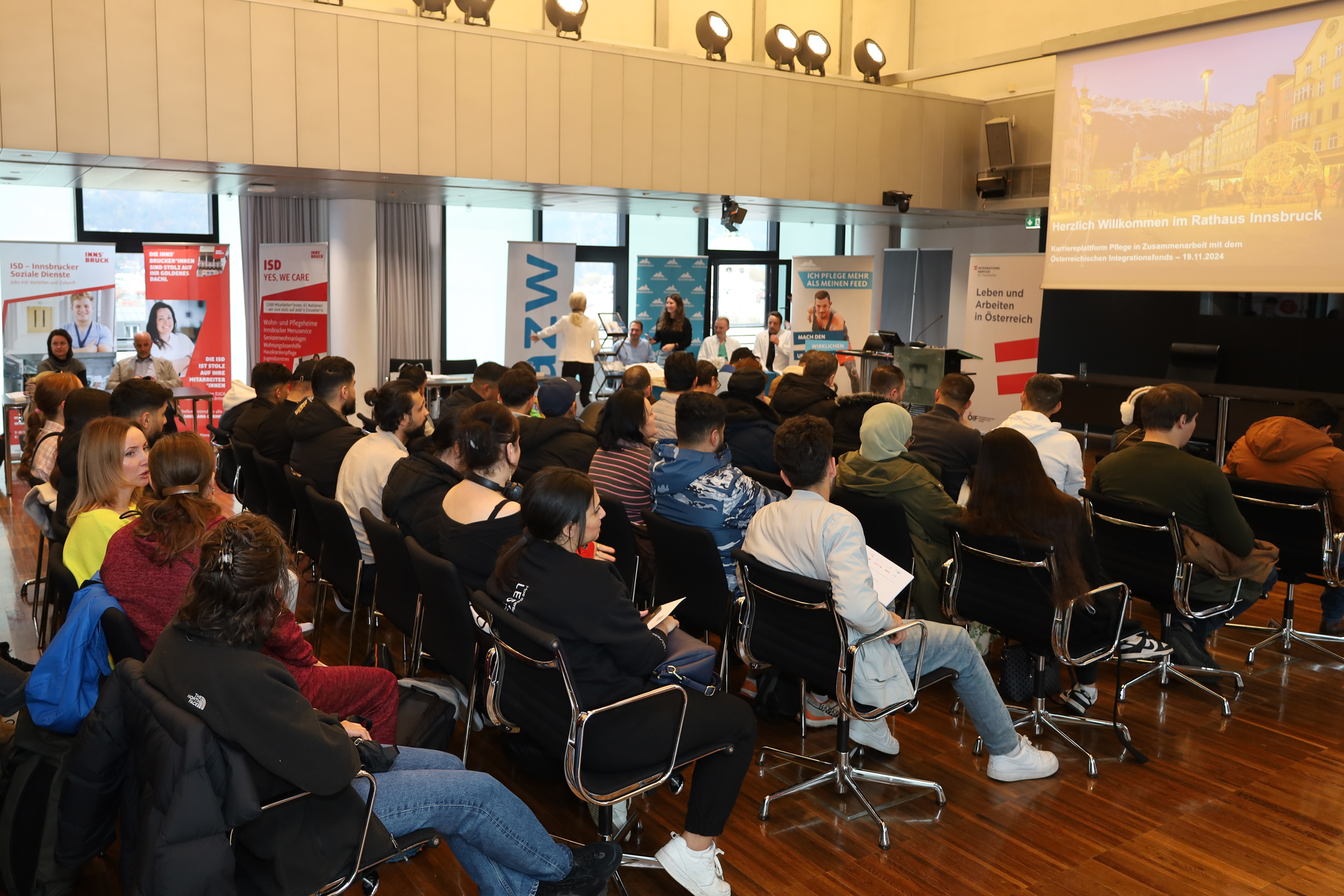 Um TeilnehmerInnen aus ÖIF-Deutschkursen über Beschäftigungsmöglichkeiten im Pflege- und Gesundheitsbereich zu informieren, organisiert der Österreichische Integrationsfonds (ÖIF) eigene Info-Veranstaltungen in ganz Österreich. Am 19. November 2024 fand die Veranstaltung im Plenarsaal des Innsbrucker Rathauses statt. Pflegekoordinator Michael Urschitz (v.r.n.l.) und Vizebürgermeister Georg Willi freuten sich gemeinsam mit Tamara Hildner (Leitung des Teams Berufschancen im ÖIF), Johanna Sebesse (Leitung ÖIF-Integrationszentrum Tirol) und Timo Andreas Bovelino (Bereichsleitung ÖIF-Integrationszentren) über das rege Interesse der TeilnehmerInnen.