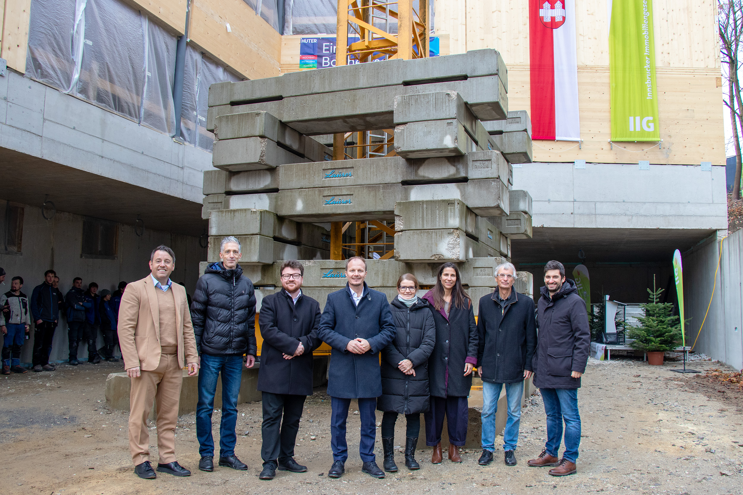 IIG-Geschäftsführer Franz Danler, Architekt Mario Gasser, Stadtsenat-Ersatzmitglied Benjamin Plach, Bürgermeister Johannes Anzengruber, Direktorin Petra Eichler, Stadträtin Janine Bex, Geschäftsführer Thomas Huter (Baufirma Huter & Söhne GmbH), Tobias Huter (Baufirma Huter & Söhne GmbH) bei der Firstfeier am Campus Arzl.
