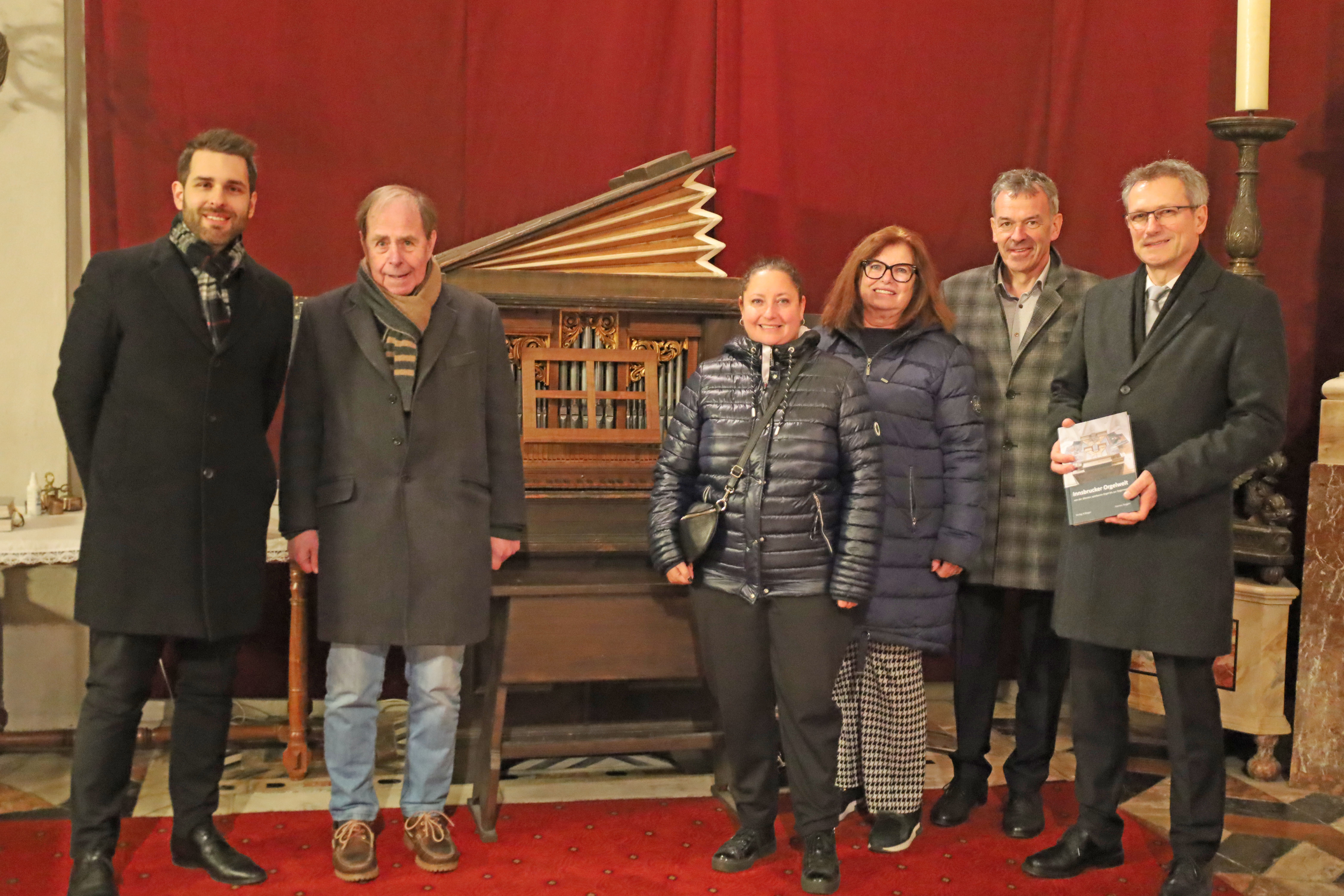 Der Autor Hannes Torggler (1. v.r.) mit (v.l.) den Organisten Elias Praxmarer und Prof. Reinhard Jaud, den Gemeinderätinnen Birgit Winkel und Marlene Trinkl und Vizebürgermeister Georg Willi vor der Humpel-Orgel in der Hofkirche.