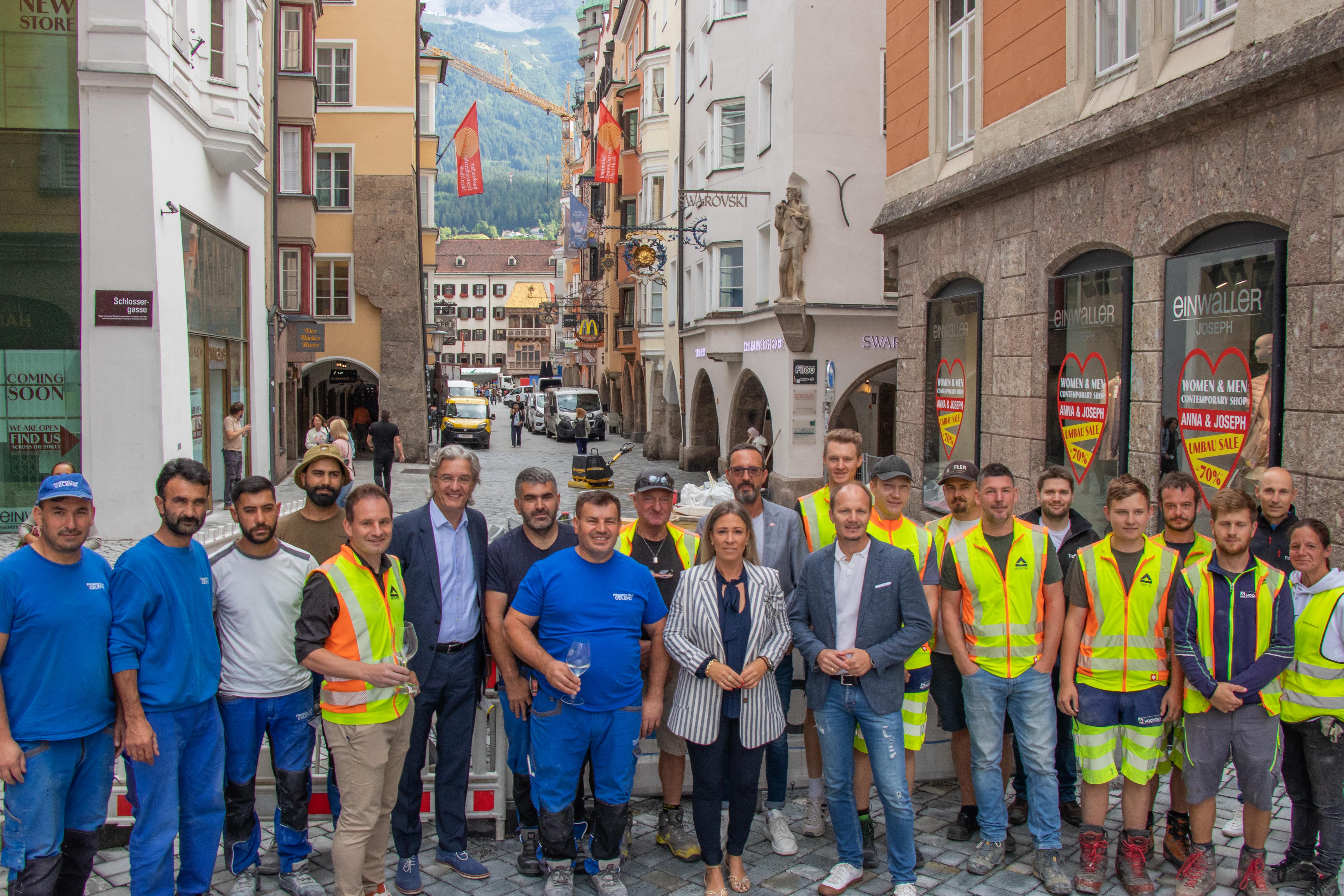 Bürgermeister Johannes Anzengruber (1. Reihe, 5. v. r.), Stadträtin Mariella Lutz (1. Reihe, 6. v. r.), Obmann Peter Paul Mölk (2. Reihe, 5. v. l., Innsbruck Tourismus), Michael Perger (2. Reihe, 2. v. l., Obmann Innsbrucker Zentrumsverein) sowie Mitarbeitende der bauausführenden Firmen und der Stadtverwaltung freuen sich über den erfolgreichen Abschluss der Altstadt-Pflasterung.