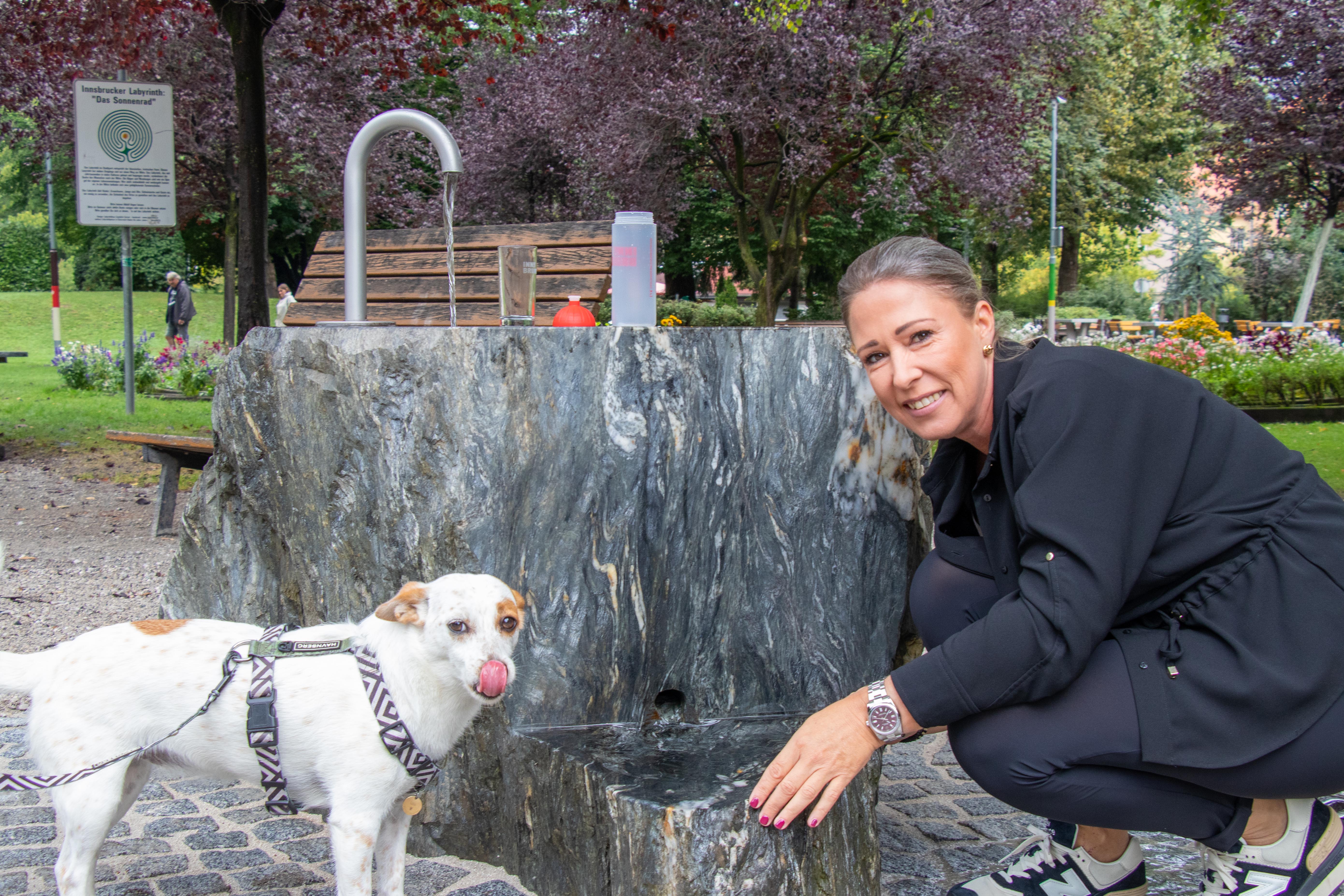 Durst gelöscht – nicht nur bei Zweibeinern: Stadträtin Mariella Lutz und ein vierbeiniger Parkgast beim „Geschmackstest“ des neuen Brunnens.