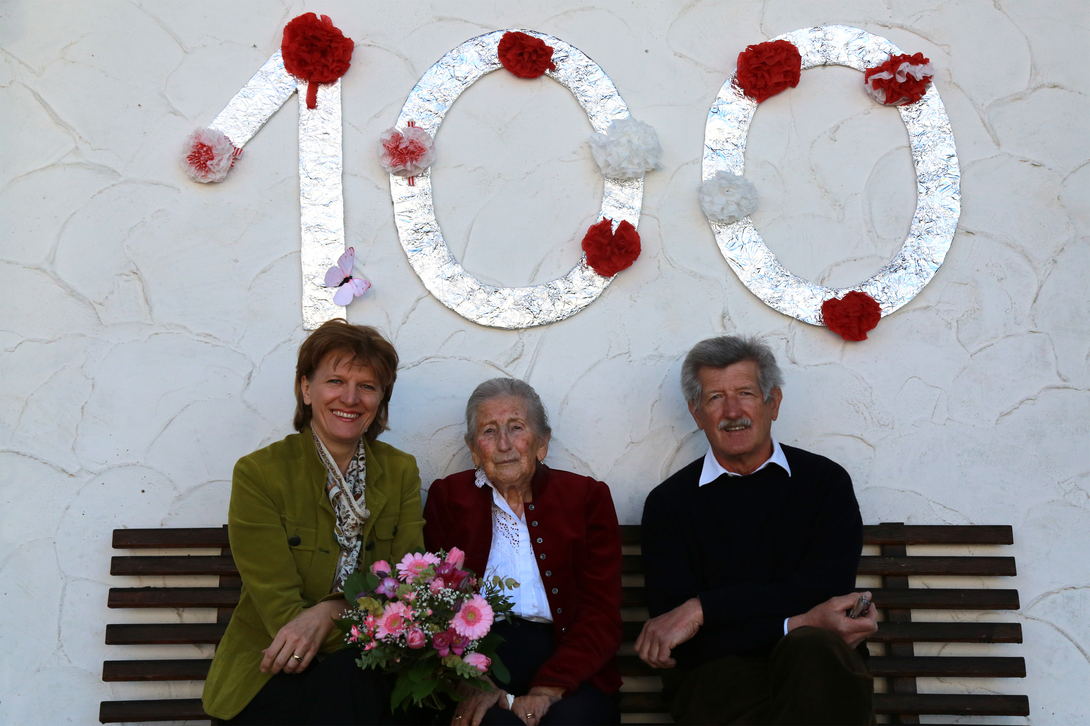 Bürgermeisterin Christine Oppitz-Plörer, Maria Profanter und ihr Sohn Max vor dem Geburtstagshunderter an dem schön gelegenen Haus der Jubilarin in Vill.