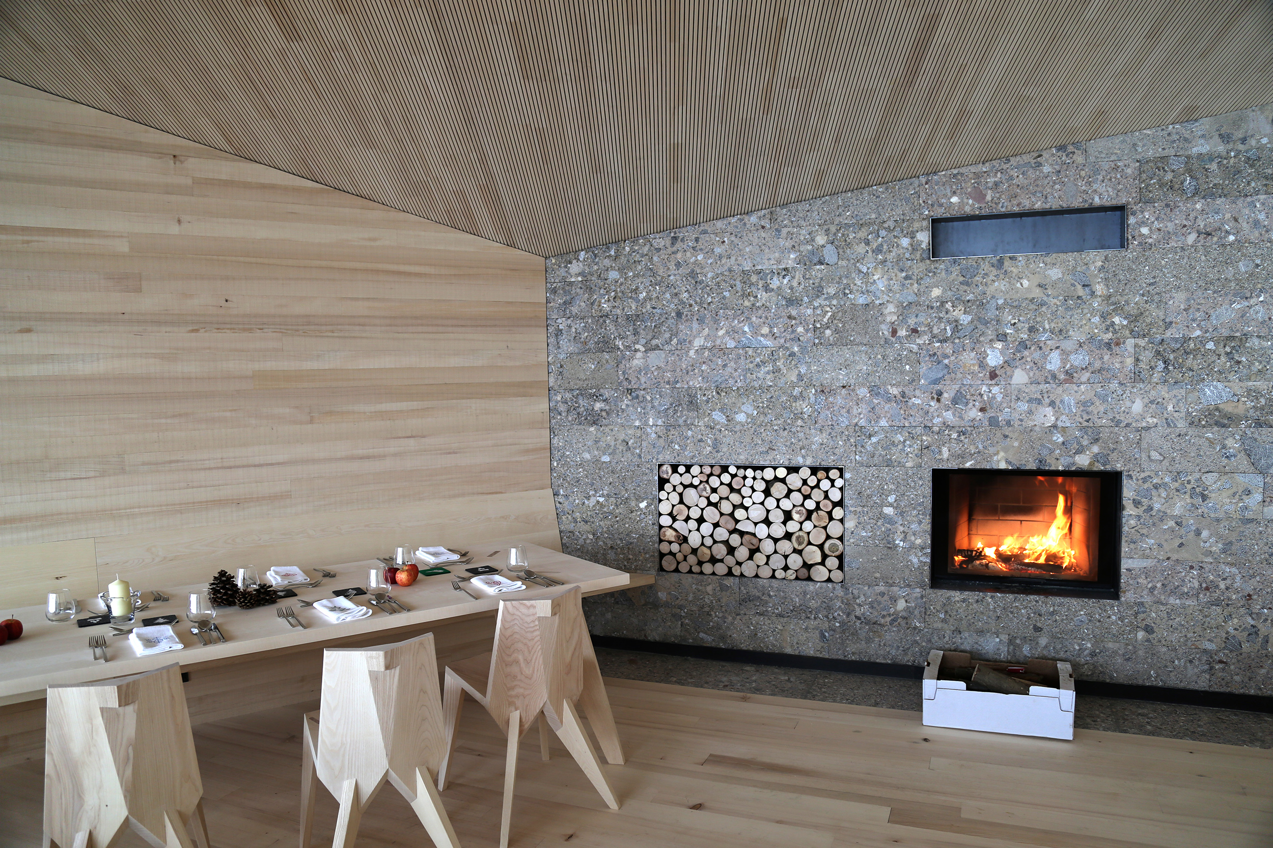 Die Kaminwand wurde mit Höttinger Breccie verkleidet und durch die Wandtäfelung mit Weißtanne wirkt der Gastraum heimelig.