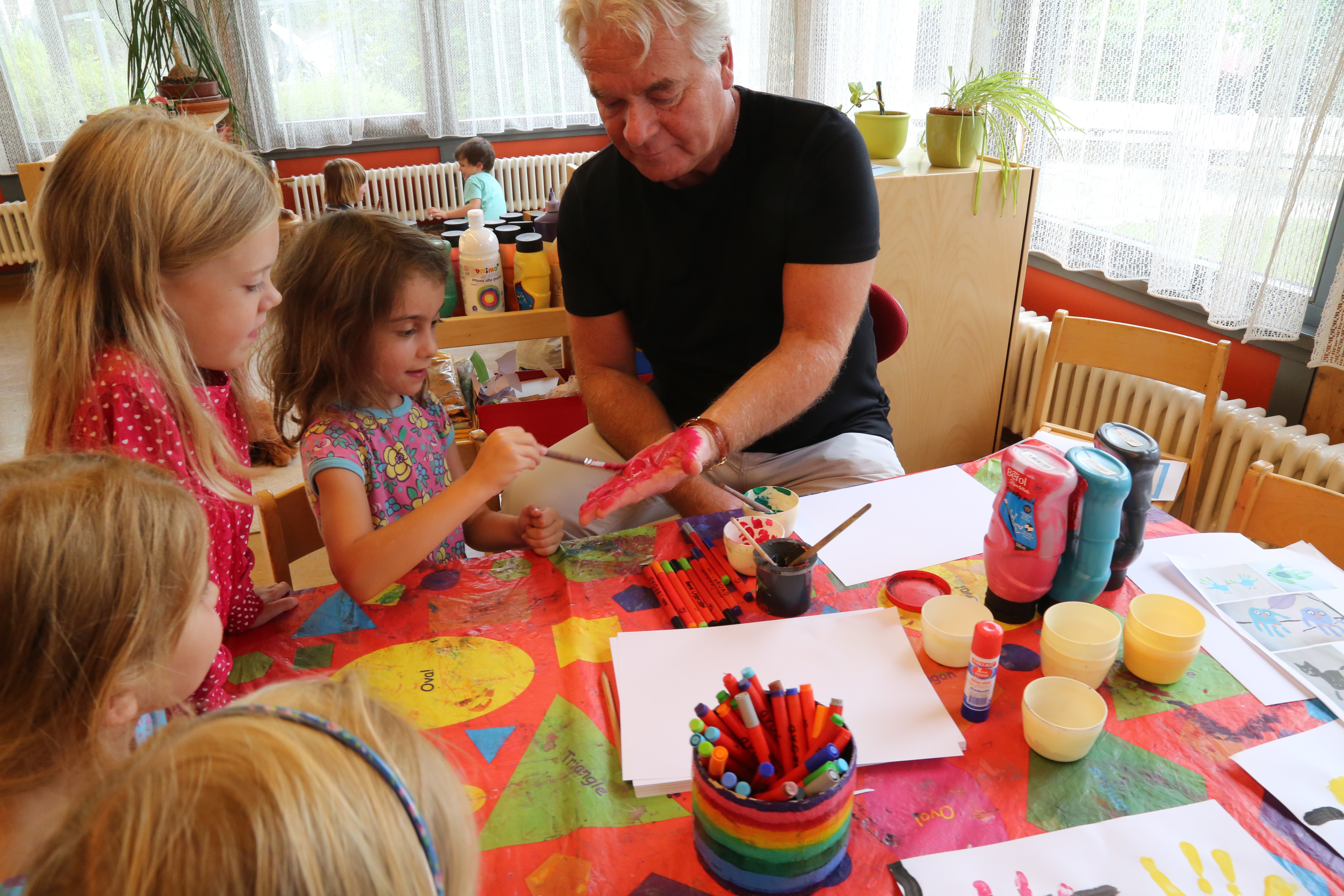 Die Kinder im Sommerkindergarten Peergründe malten Bildungsstadtrat Ernst Pechlaner die Hand mit Farben an, um mit ihm Eulen, Katzen und kleine Monster aus den Handabdrücken zu zeichnen.